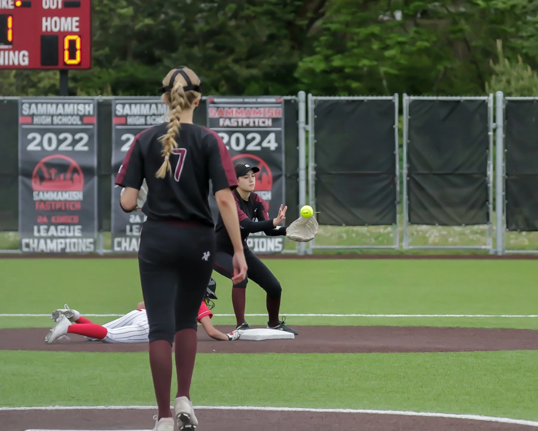 Islander softball players follow an infield play near a base.