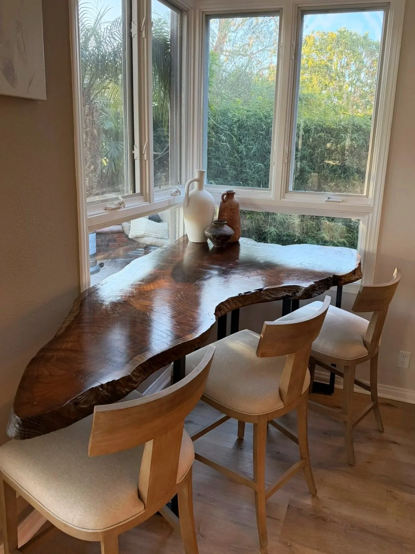 Custom live-edge slab dining table overlooking garden views.