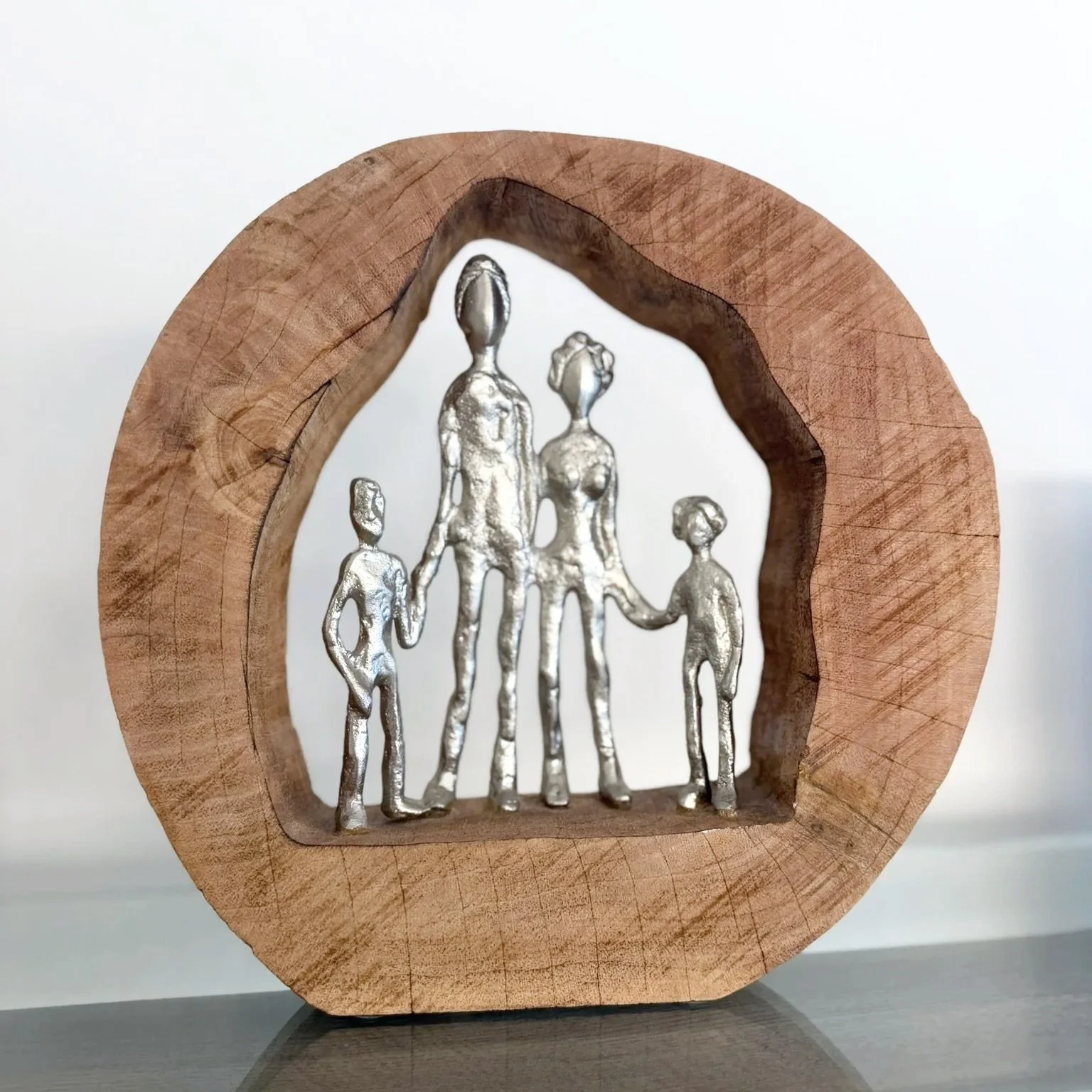 Decorative wooden sculpture featuring a family of four within a house-shaped frame.