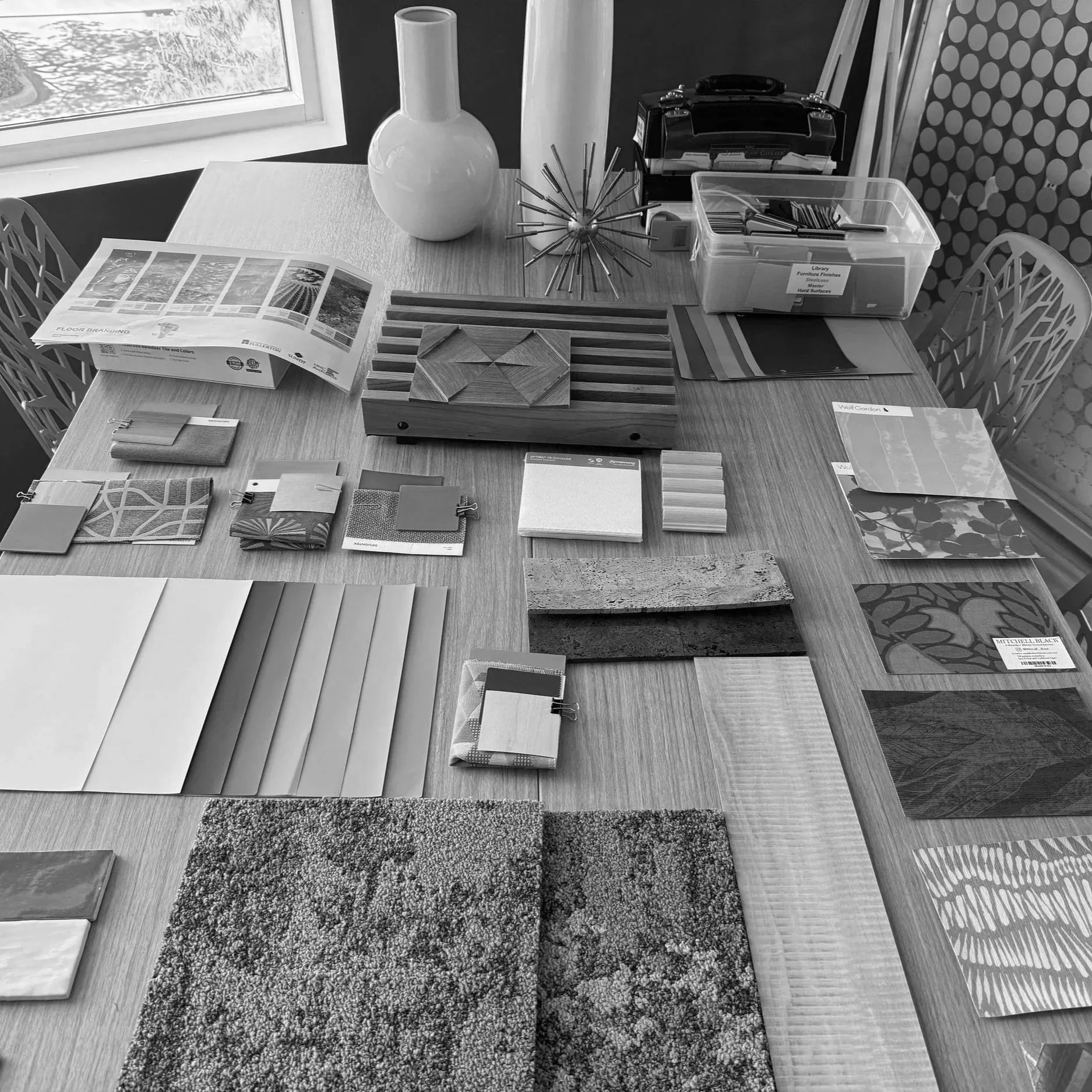 Interior design materials, finish samples, and architectural references arranged on a worktable during the design process at HMC Architects.