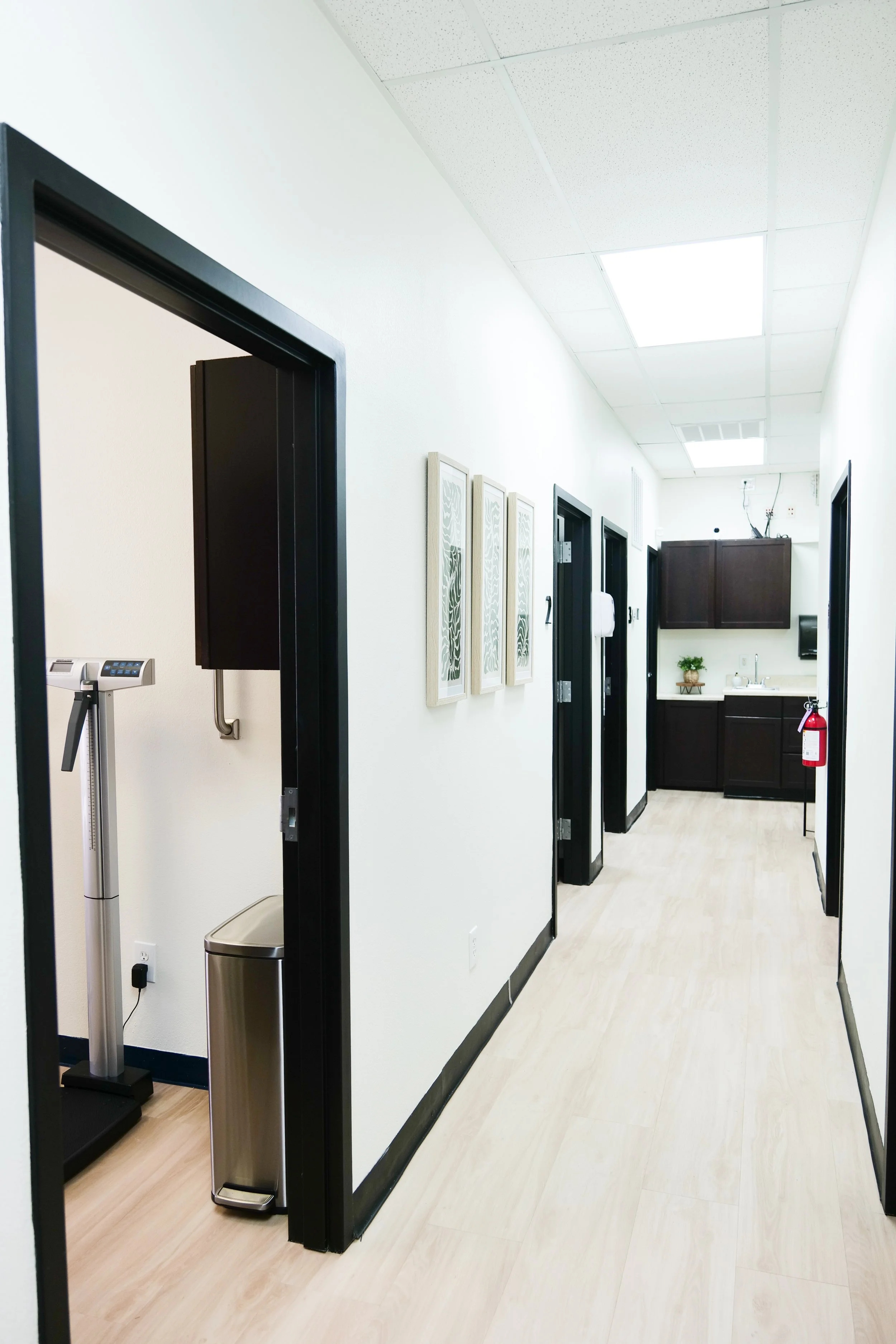 Medical Clinic hallway with framed artwork on the walls, and an automatic blood pressure monitor on the left.