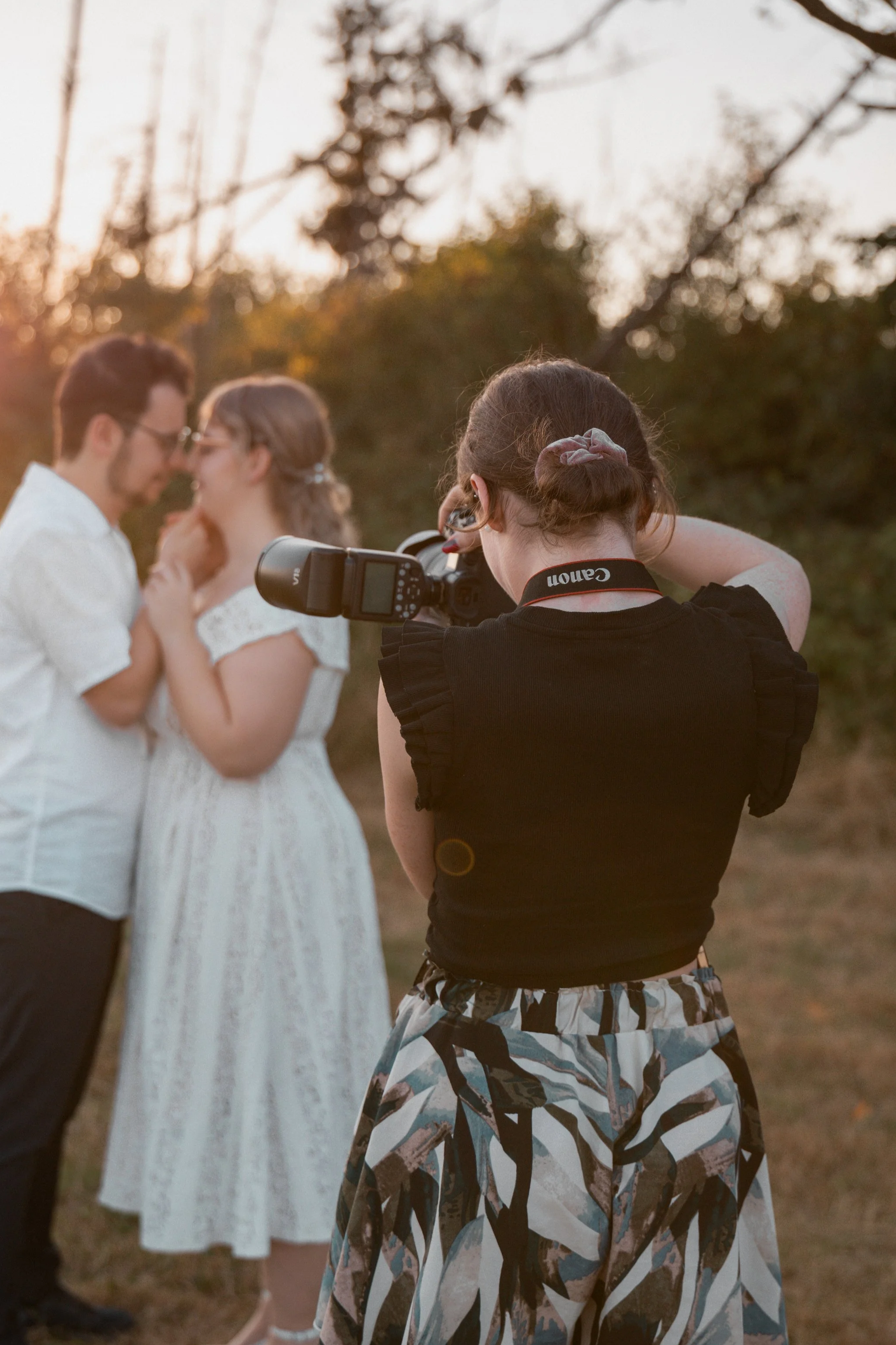 Eine Fotografin fotografiert ein Paar, das sich liebt, im Freien bei Sonnenuntergang. Sunset-Shooting, Sunset Shooting, Golden Hour Shooting, Golden Hour-Shooting.