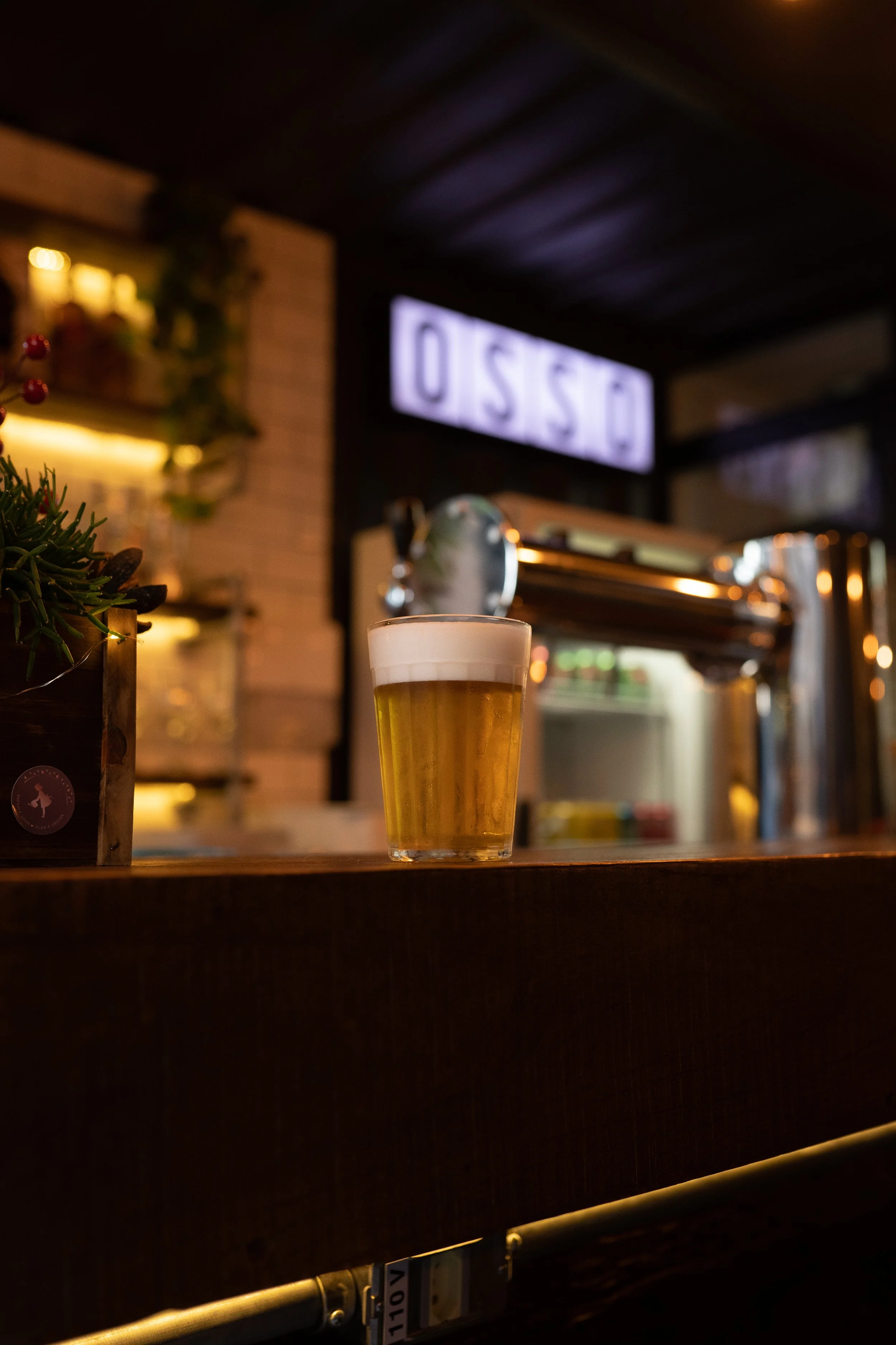 Copo de chopp no balcão do Osso Parrilla Bar em Canoas, com o letreiro OSSO ao fundo