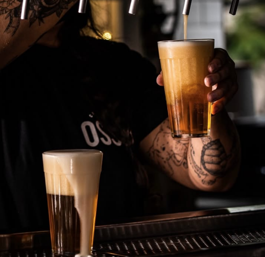 Chopp sendo tirado na torneira, com copo cheio em primeiro plano