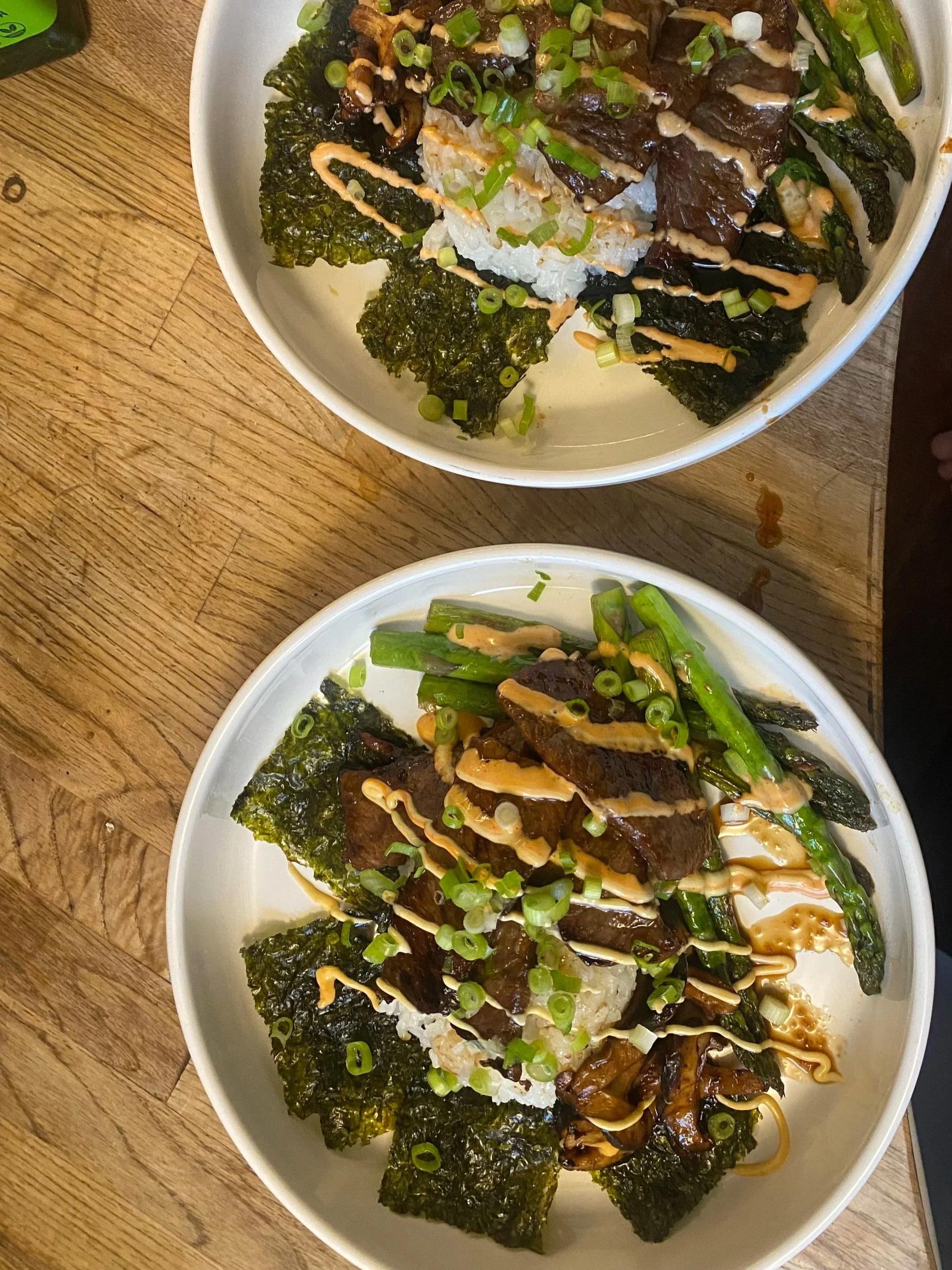 Japanese sushi roll topped with sliced green onions, drizzled with spicy mayo and eel sauce, served with seaweed salad on the side.