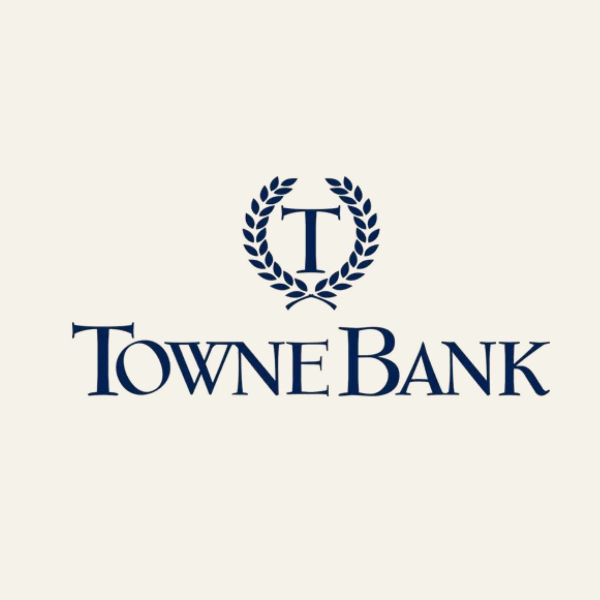 Logo of Town & Tower Bank featuring a large blue letter "T" within a laurel wreath on a white background.
