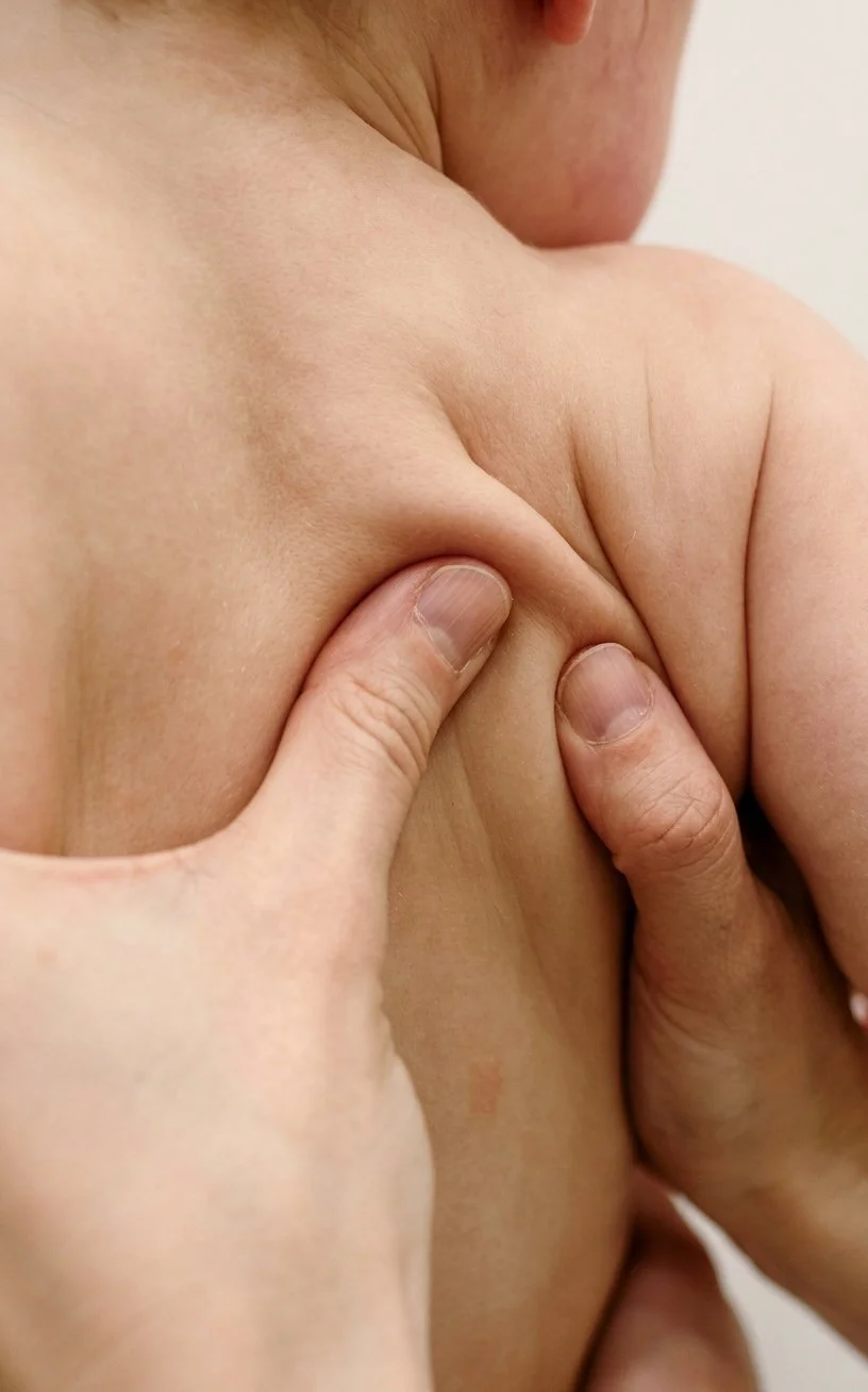 Close-up of a person holding their shoulder with one hand.