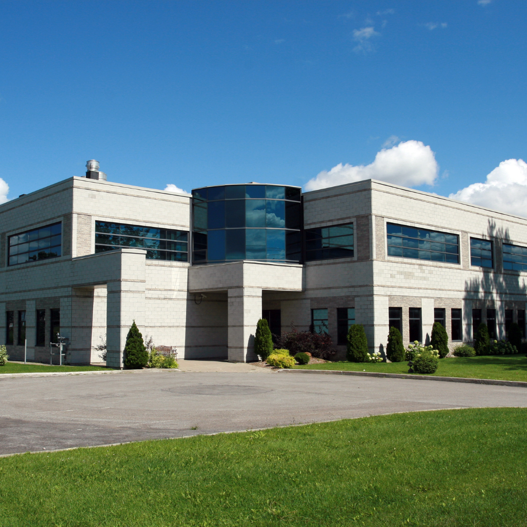 Modern commercial building with large windows and a well-maintained lawn.