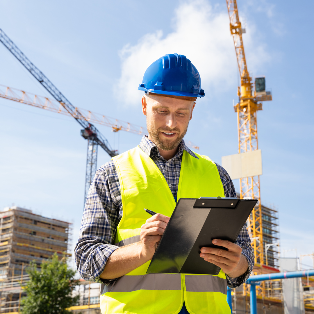 Construction worker in a safety vest and helmet inspecting building plans at a construction site