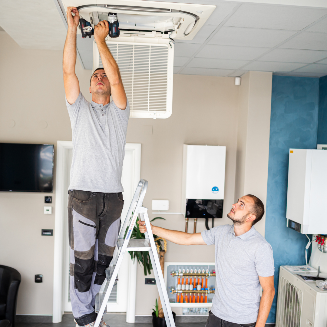 Handyman fixing an HVAC system inside a residential or commercial space.