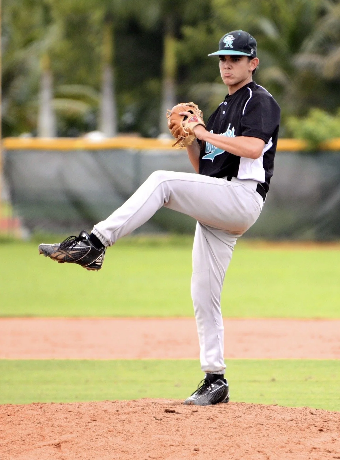 Young baseball athlete pitching during a competitive baseball game.