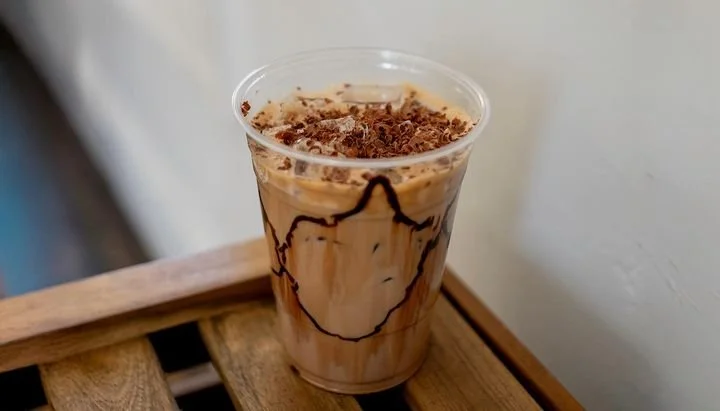 Chocolate mocha iced coffee in a clear plastic cup with chocolate syrup drizzle