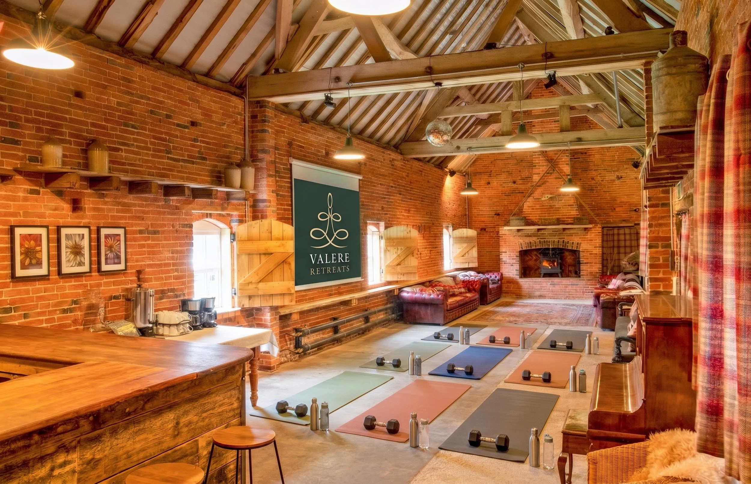 Interior of the beautifully restored Valere Retreats heritage barn studio in Staffordshire, showcasing exposed brickwork, soaring timber beams, and yoga mats prepared for an active movement class.