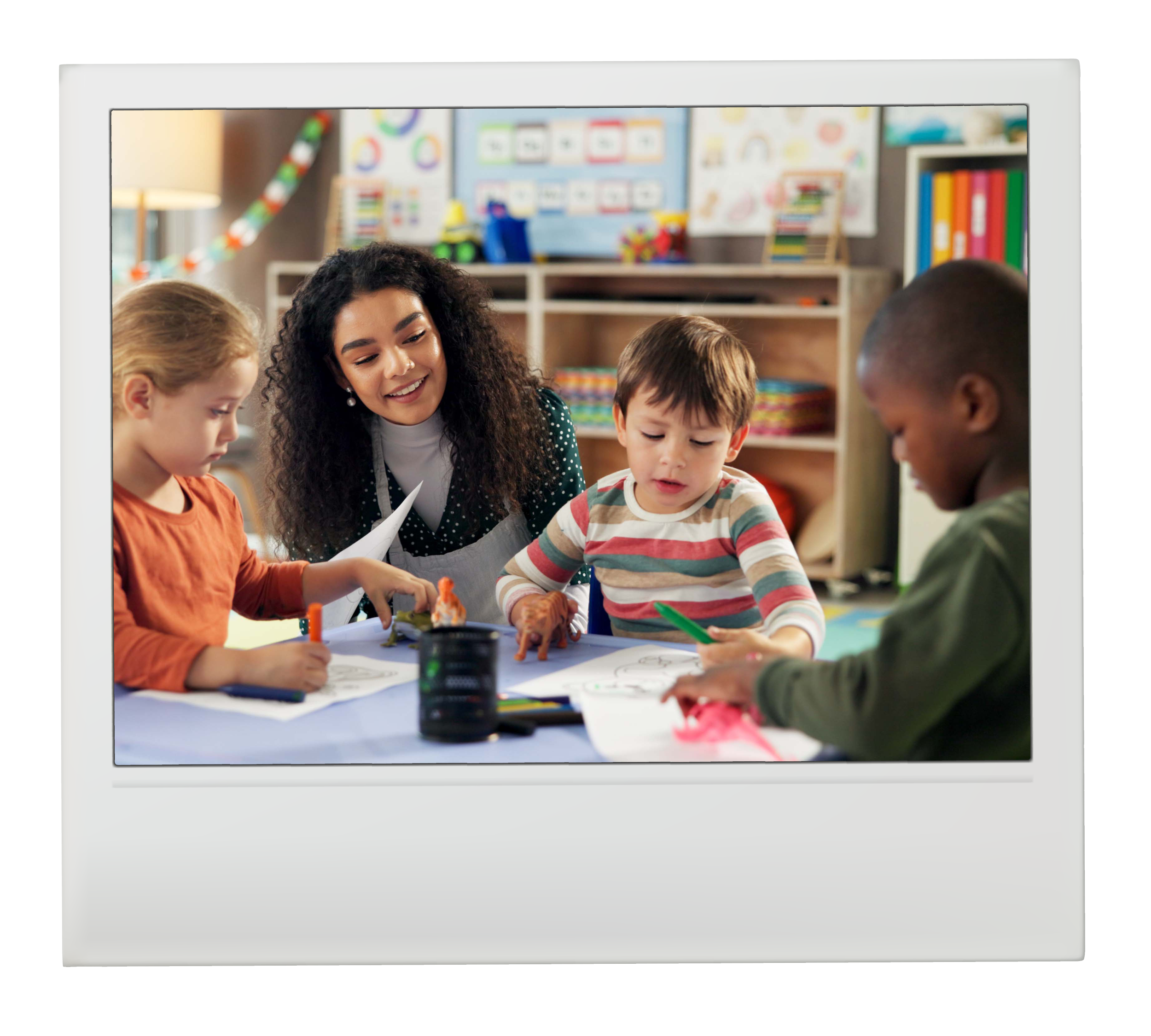 Children and a woman engaged in an activity at a classroom table, with educational posters and shelves in the background.