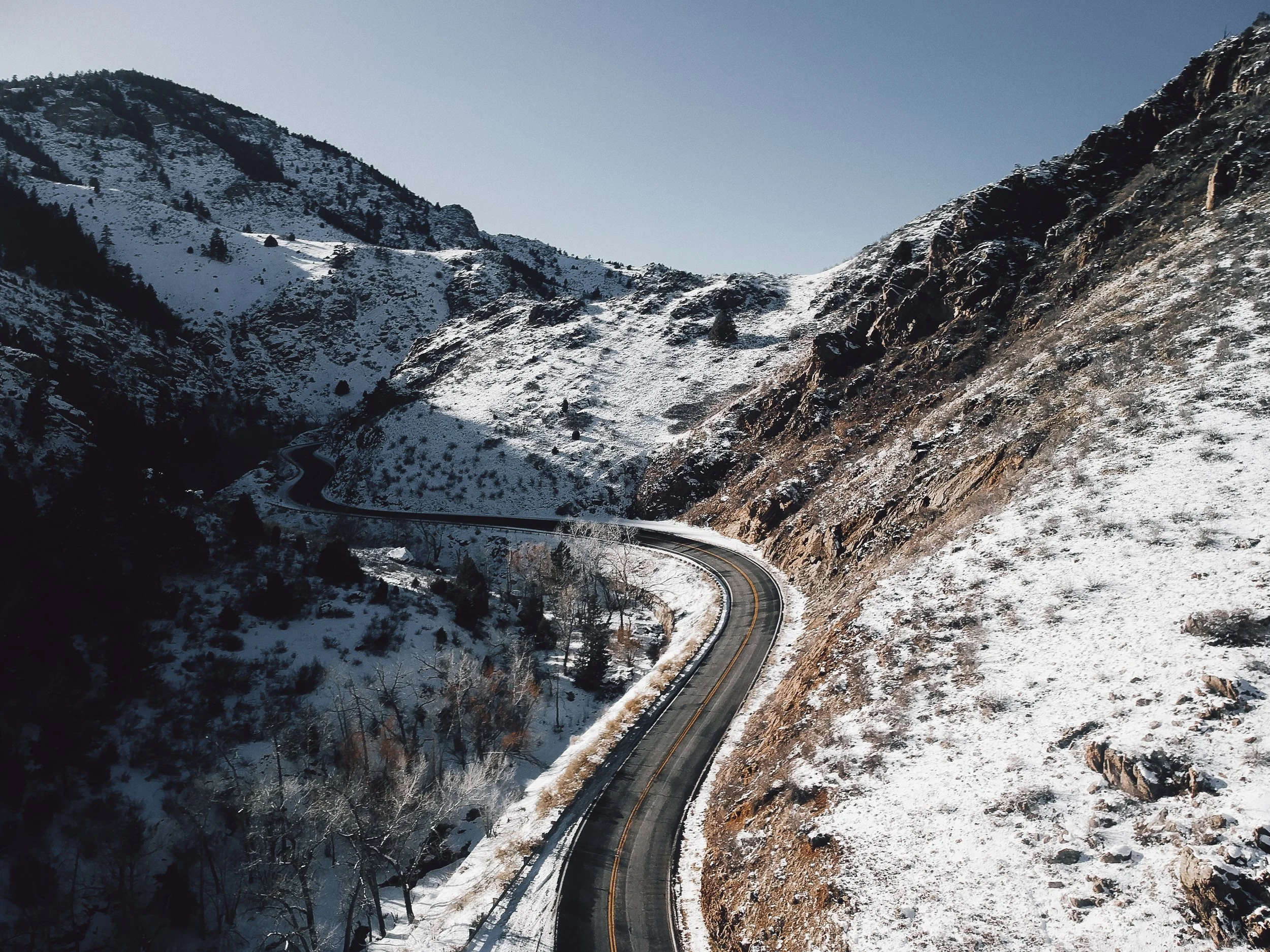 Snow-covered mountains and a winding road through a mountain valley.