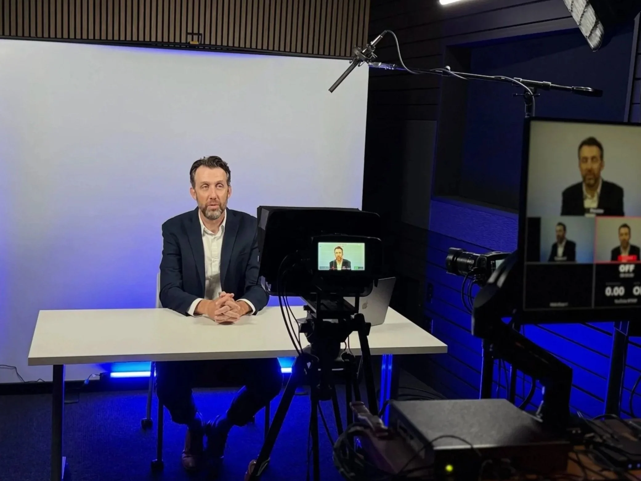 Presenter at a desk recording to camera with a teleprompter on The Hawthorne set at Studio TwentyOneTwelve in Portland