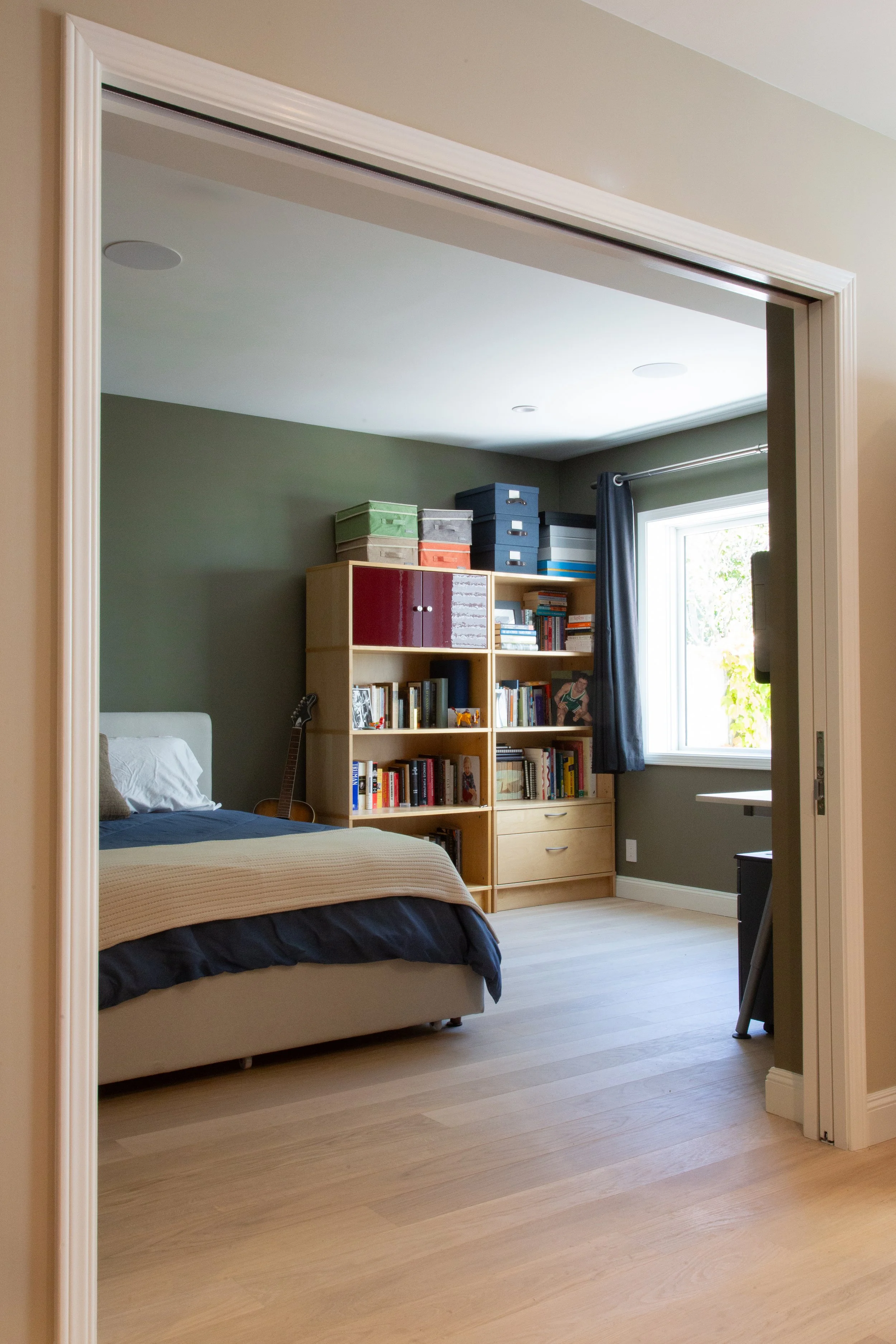 Bedroom with built-in bookshelf seen through a pocket door