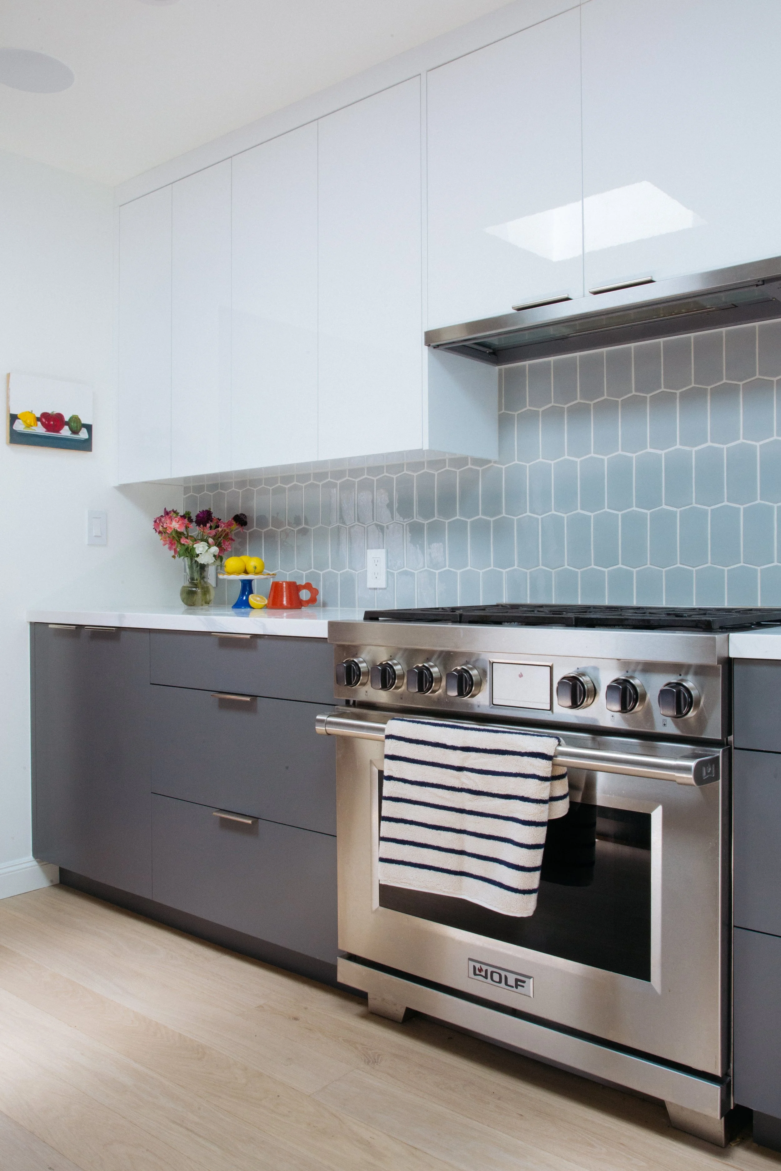 Professional range in a kitchen remodel with gray cabinets and blue tile backsplash