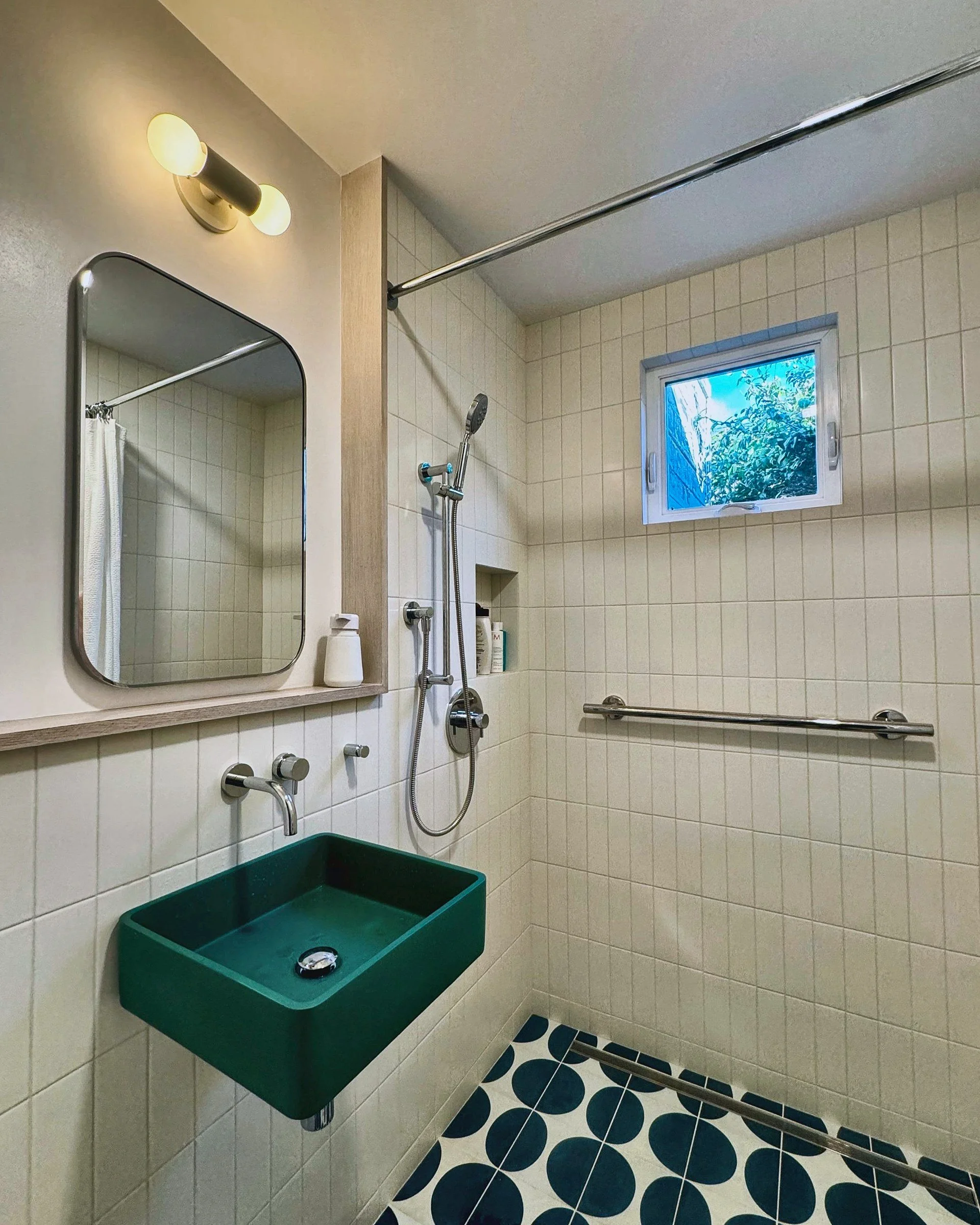Accessible bathroom with green wall-mounted sink, grab bar and patterned floor tile