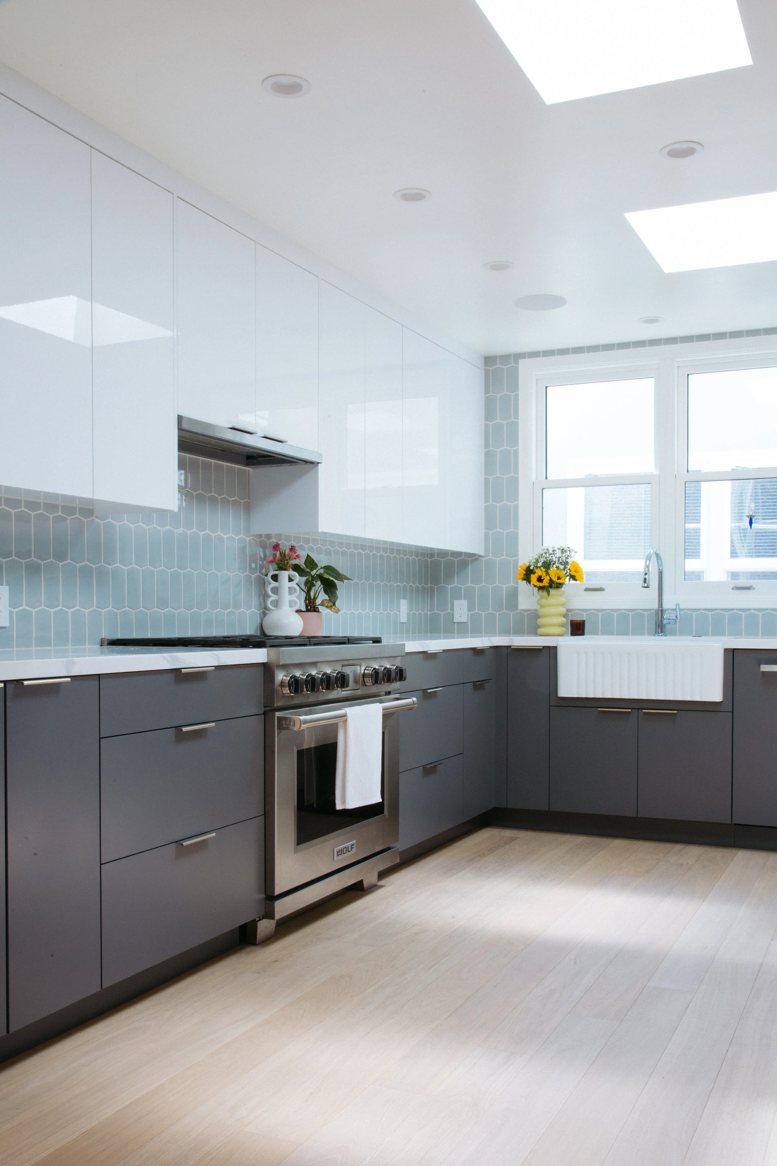 Kitchen remodel with gray lower cabinets, white gloss uppers and blue hex tile backsplash