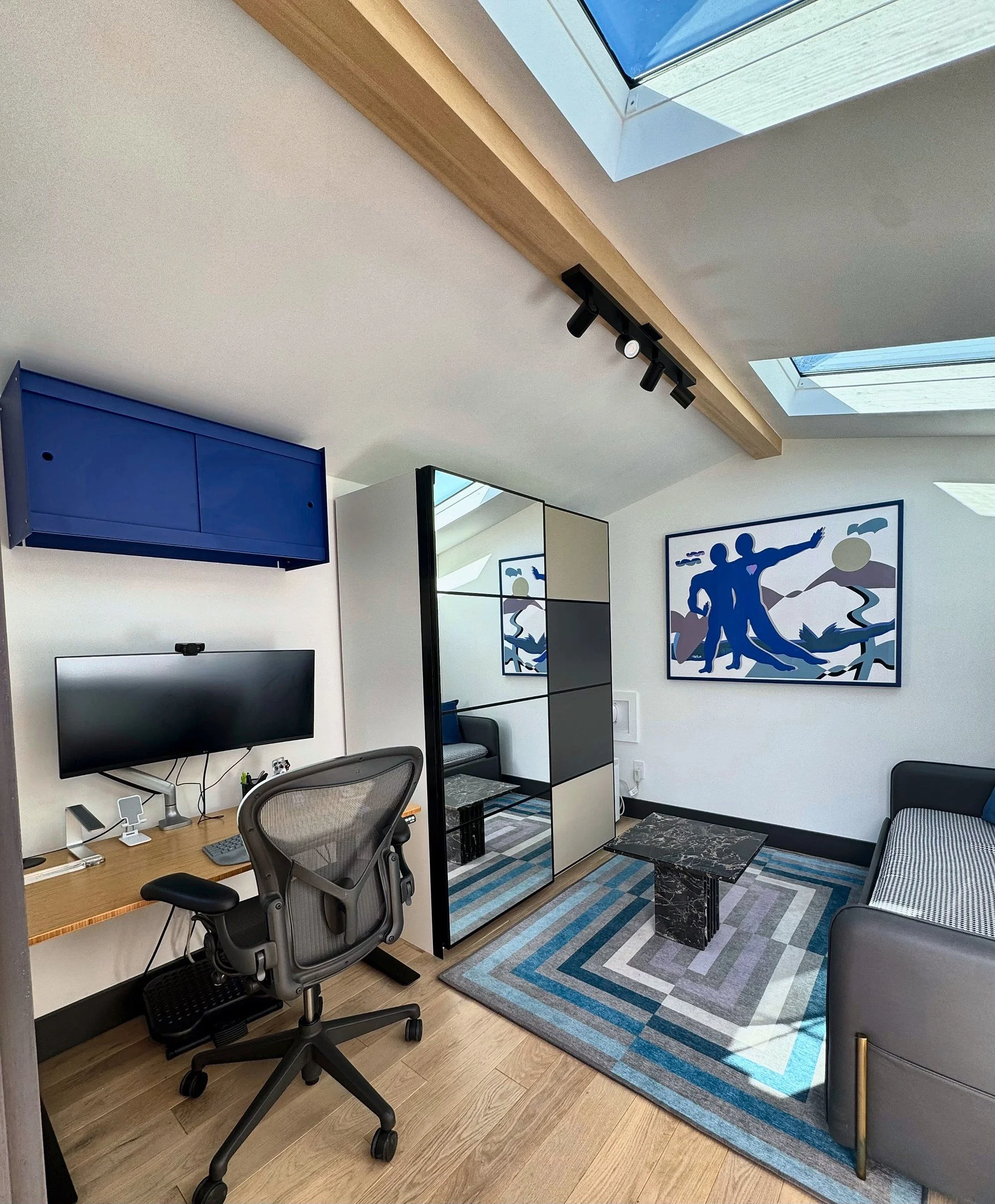 Backyard office with skylights, exposed wood beam, track lighting and blue cabinets in San Francisco