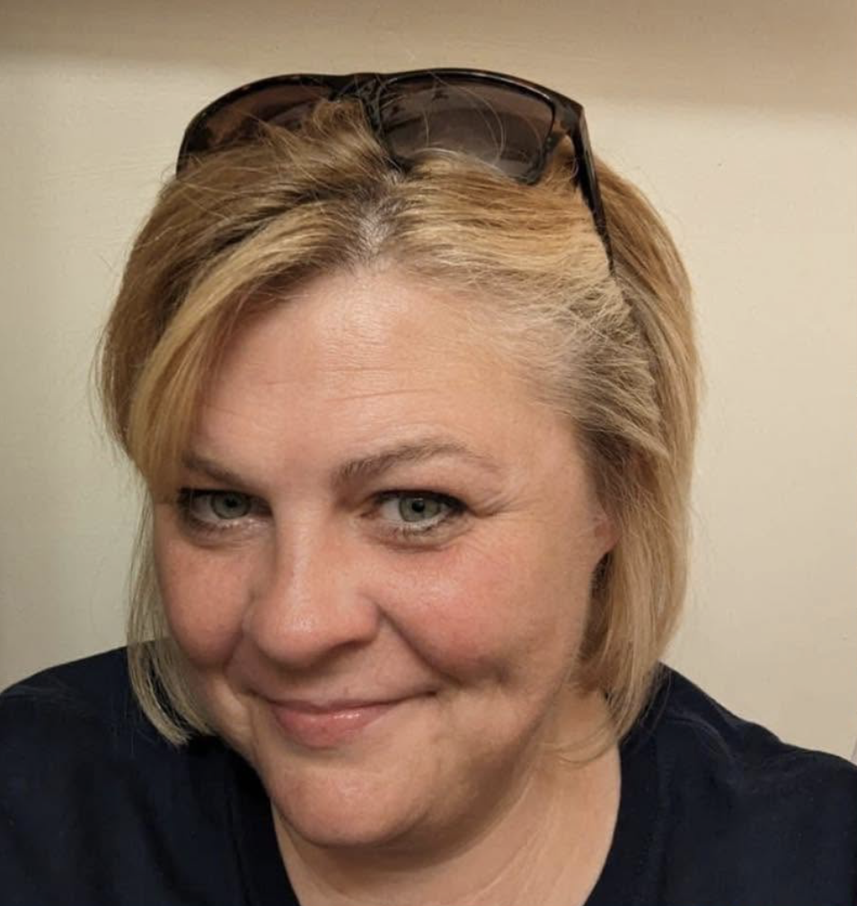 Picture of a woman smiling at the camera with sunglasses on her head