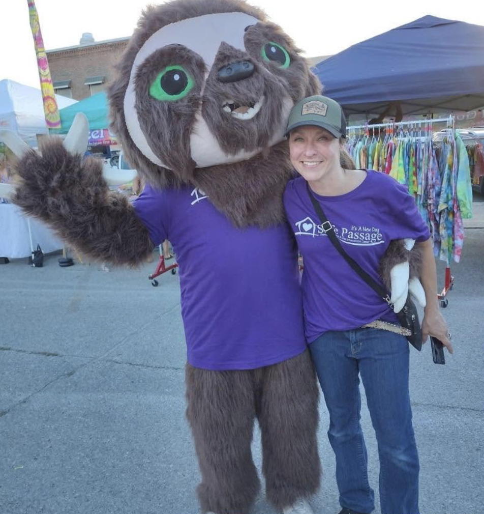 Picture of a woman in purple shirt with a sloth mascot