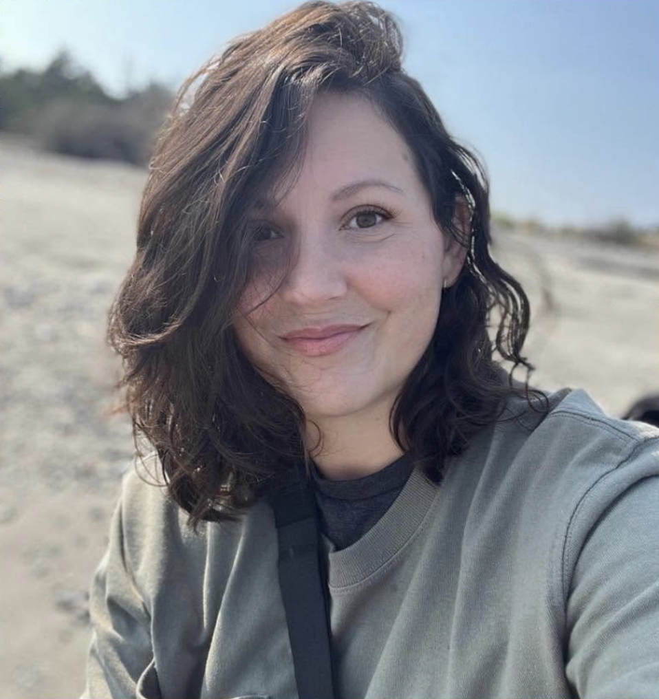 Picture of a woman with wavy hair and a big smile outside 