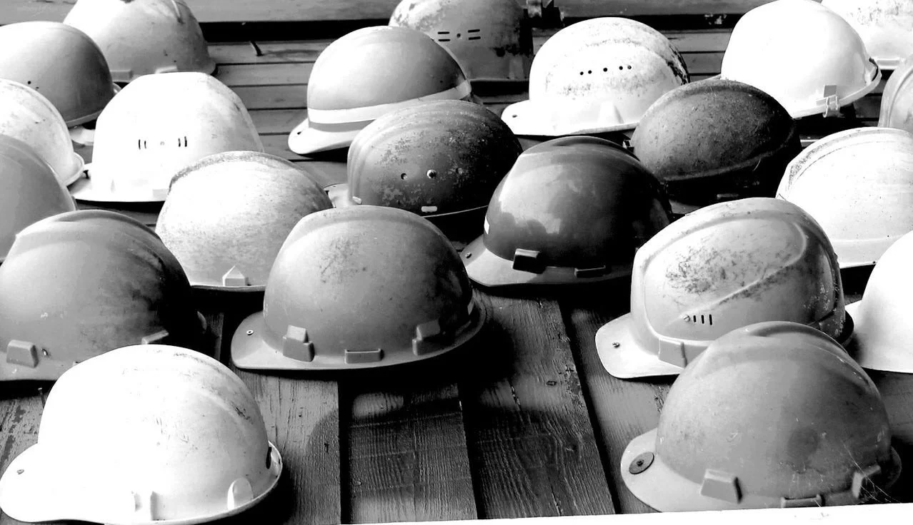 A large collection of safety helmets on a wooden surface.