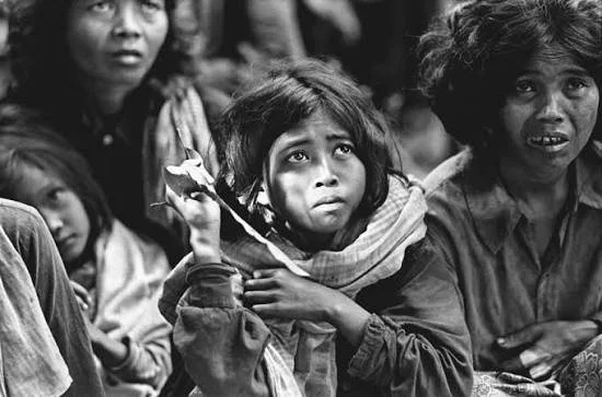 Group of children with serious expressions, some looking sad, in black and white.