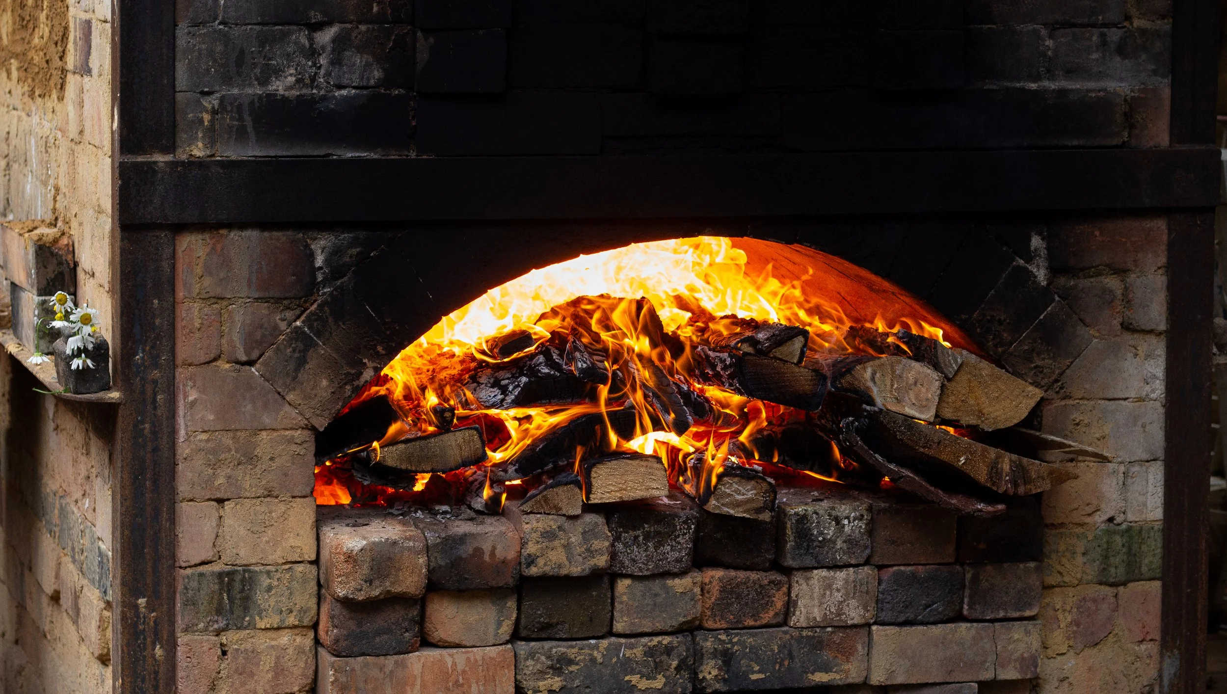A brick fireplace with a fire burning inside, with flames and logs visible.