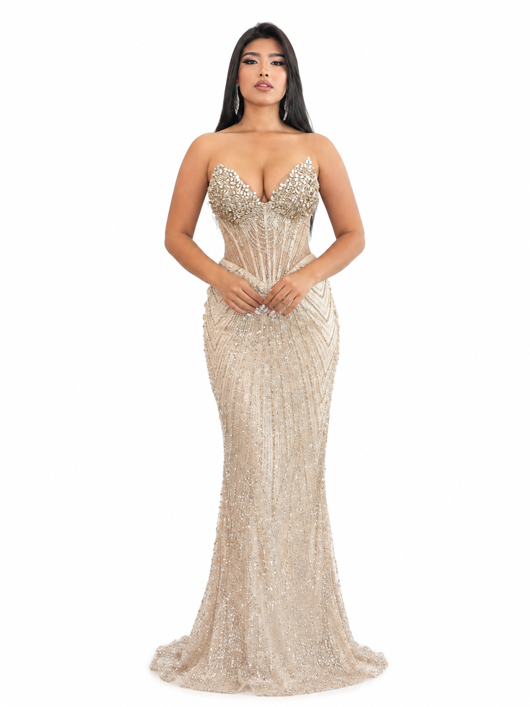 A woman in a glamorous beige, gold, and silver beaded evening gown with a plunging neckline, standing against a plain white background.