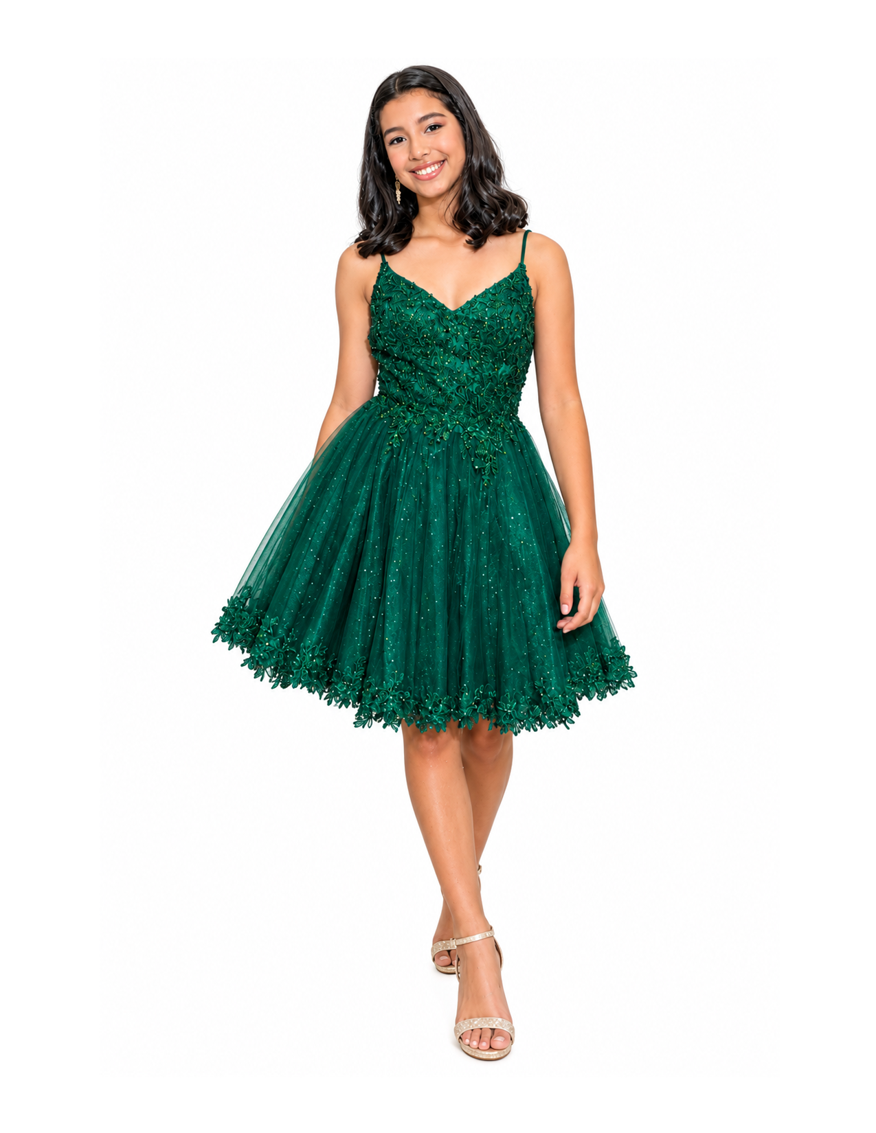 Young woman with dark wavy hair smiling, wearing a green dress with intricate detailing and a full skirt, standing against a white background.