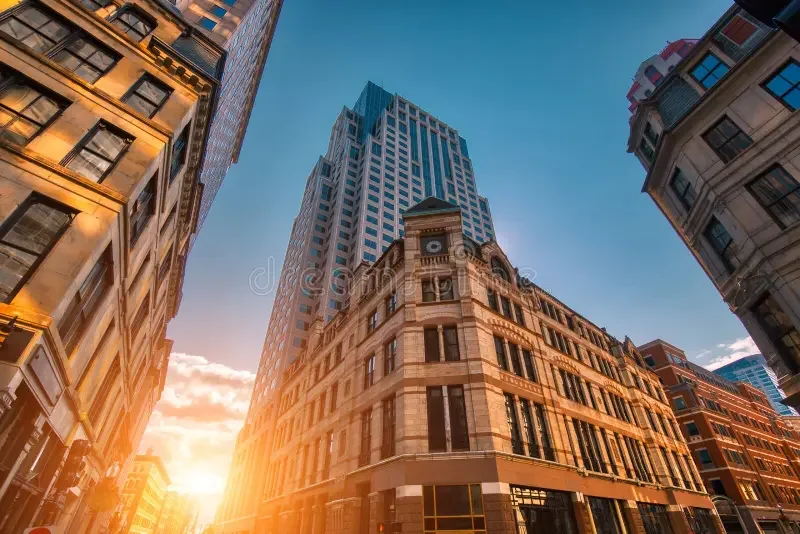 View of tall city buildings and skyscrapers at sunset in a downtown area.