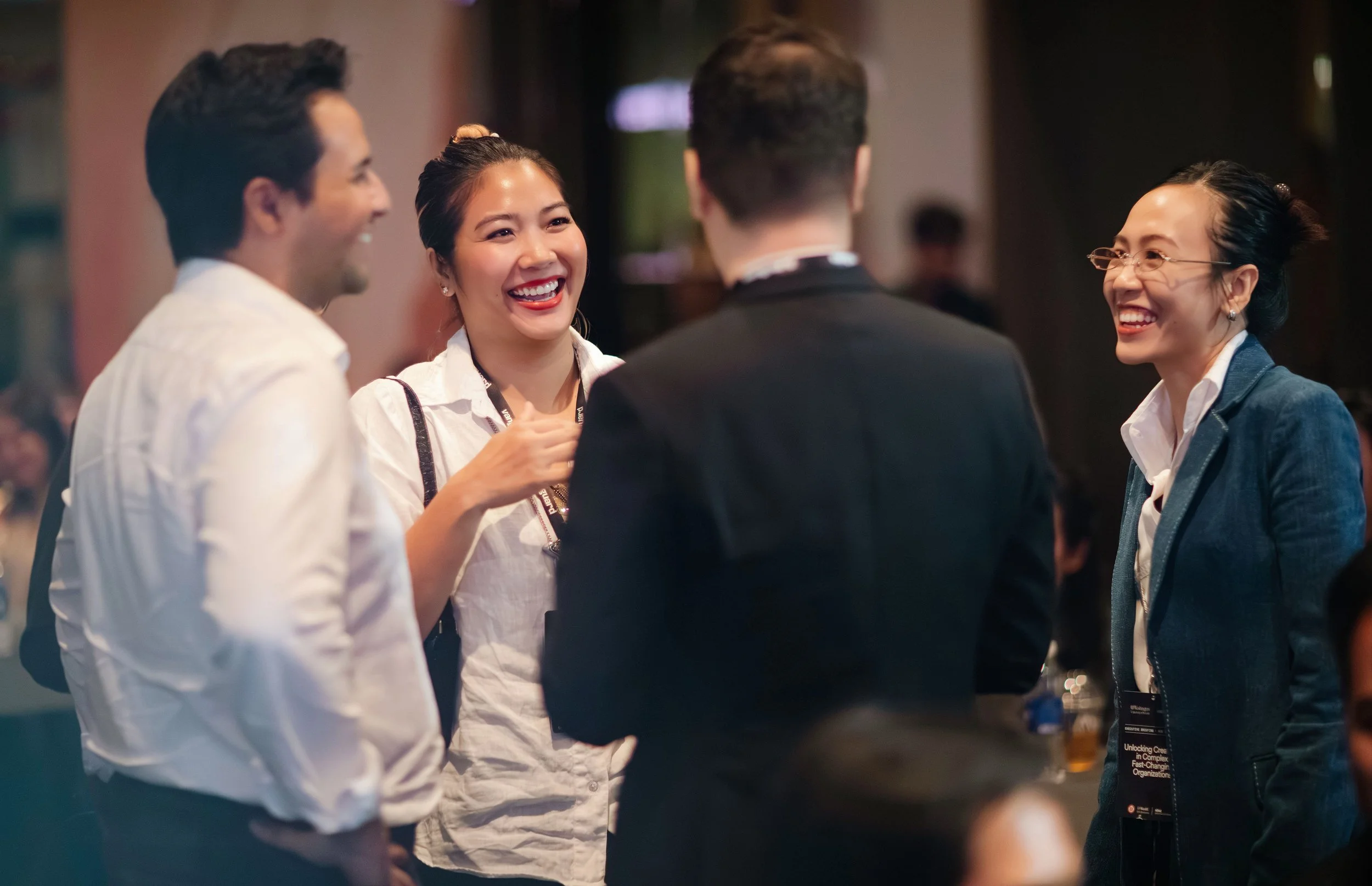 Four people sharing a laugh at a professional event or conference.