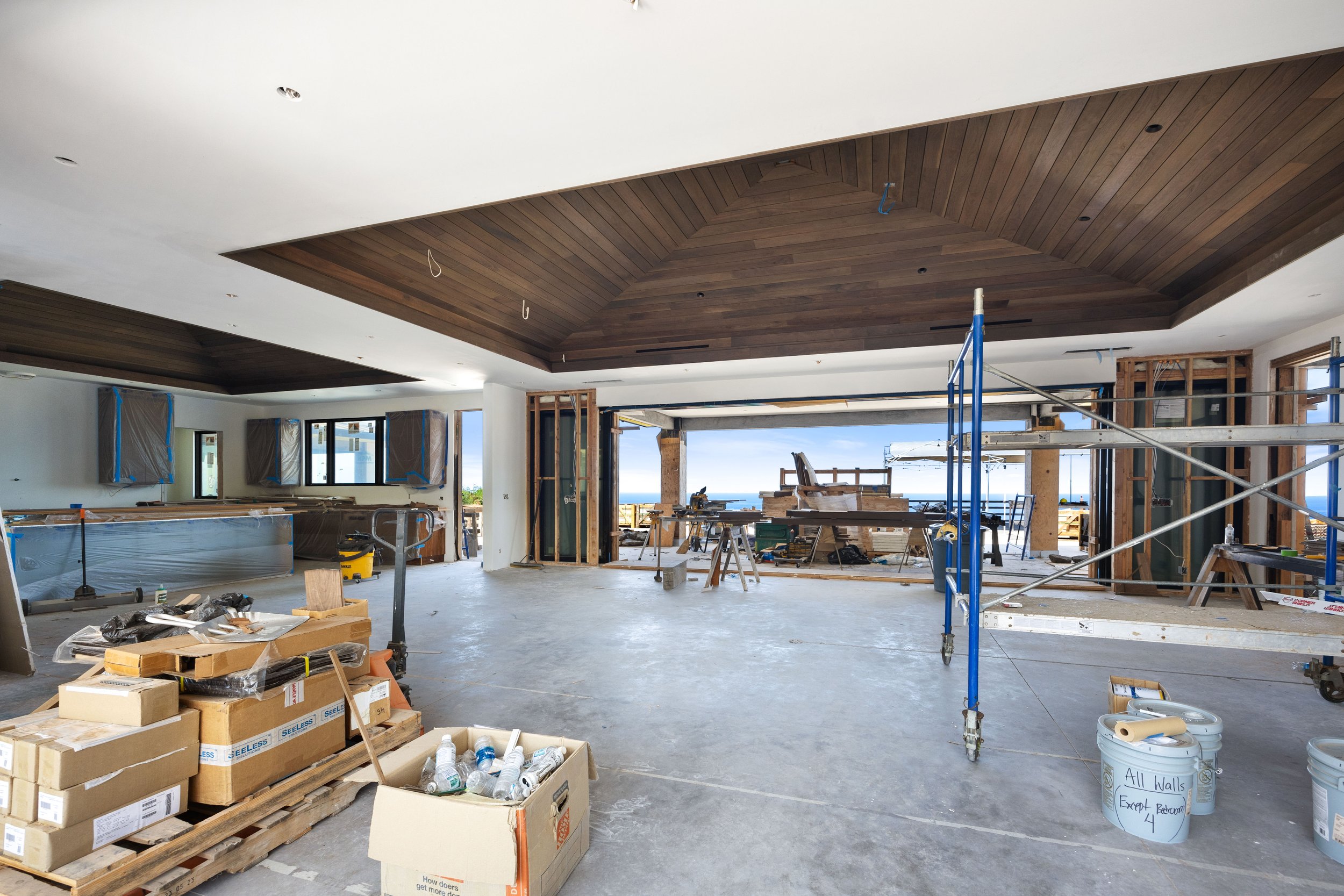Construction site of a residential interior with a wooden ceiling, open walls, and construction tools and materials scattered around.