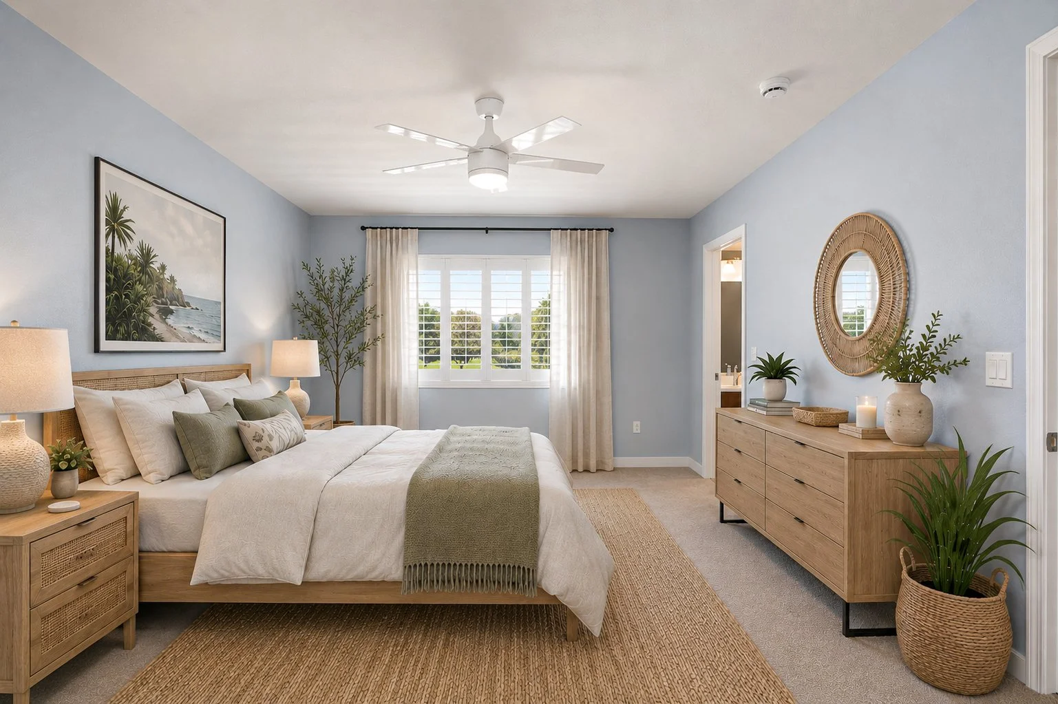 A bedroom with light blue walls, a large window with white shutters and beige curtains, a wooden bed with white and green pillows, a beige bedspread, and a blanket. There are two nightstands with lamps, a dresser with decorative items, potted plants,