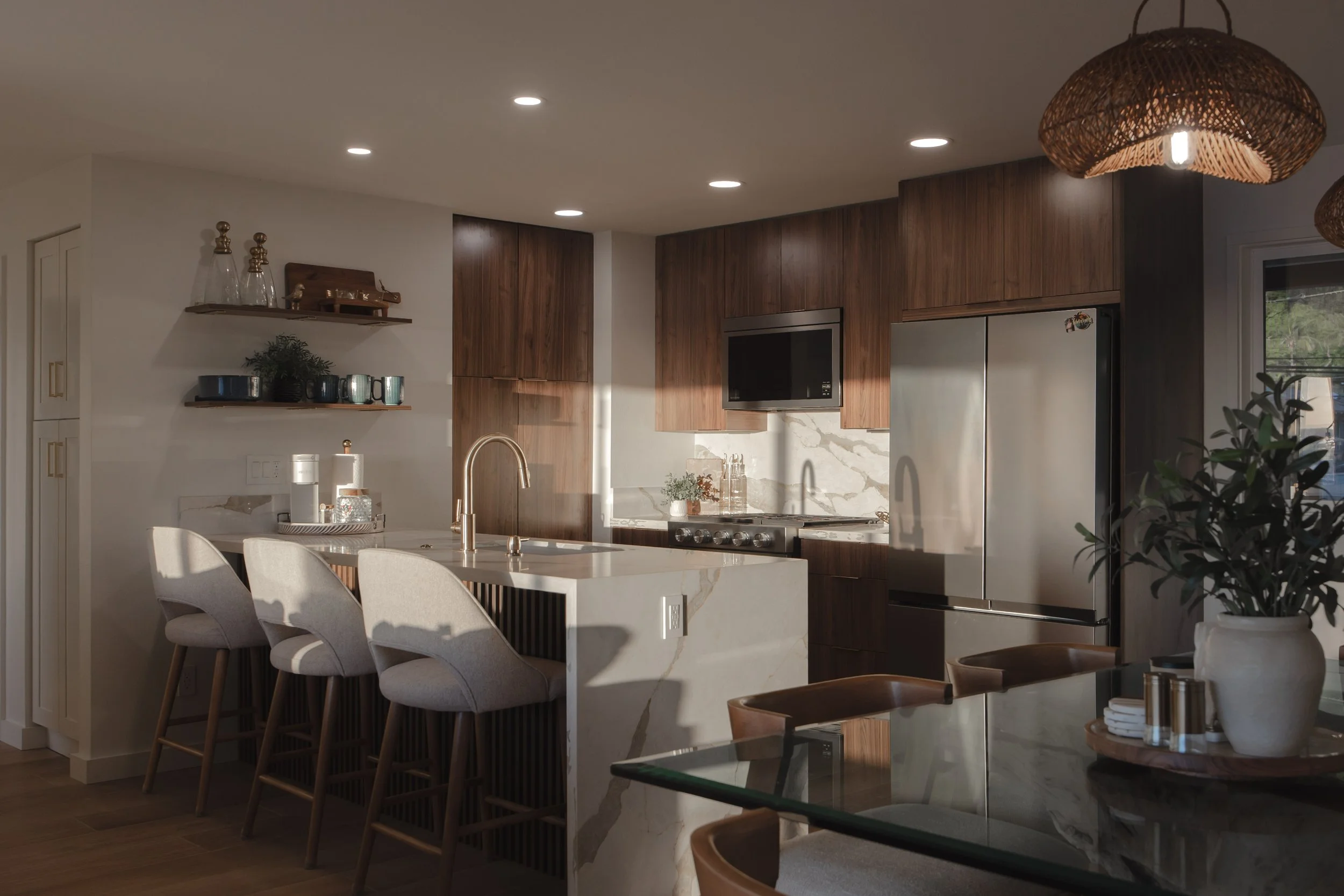 Modern kitchen with wood cabinets, stainless steel refrigerator, marble backsplash, and seating area with four upholstered chairs and a marble island