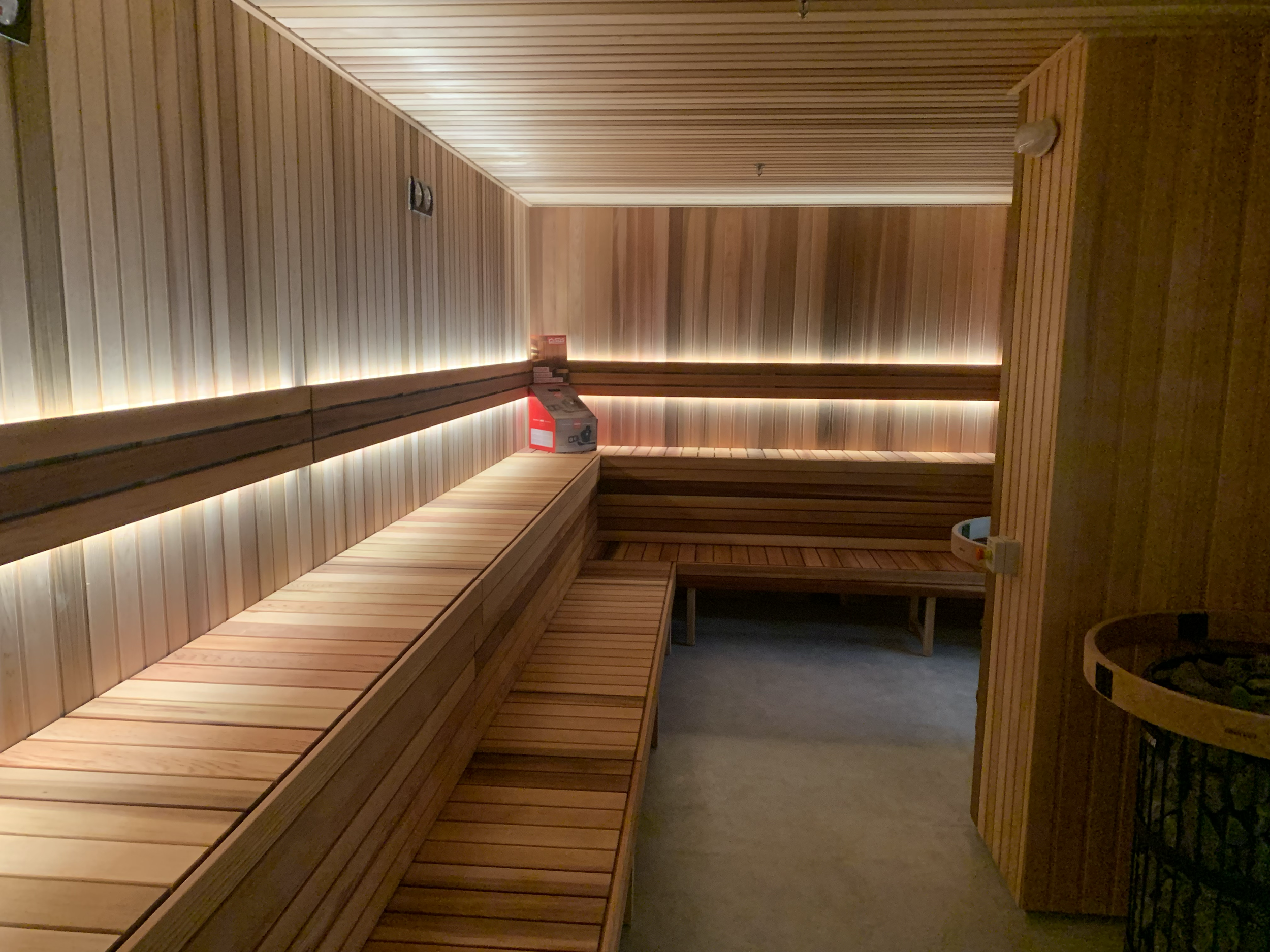 Empty wooden sauna interior with benches and a small box on the bench.