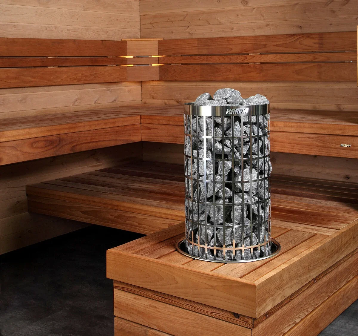 A sauna room with wooden benches and walls, featuring a cylindrical metal heater filled with rocks.