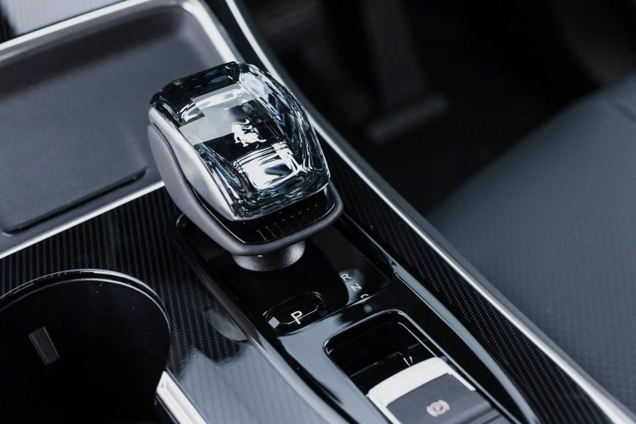 Close-up of a modern luxury car's center console with a crystal gear shifter, electronic parking brake, and gear indicator.