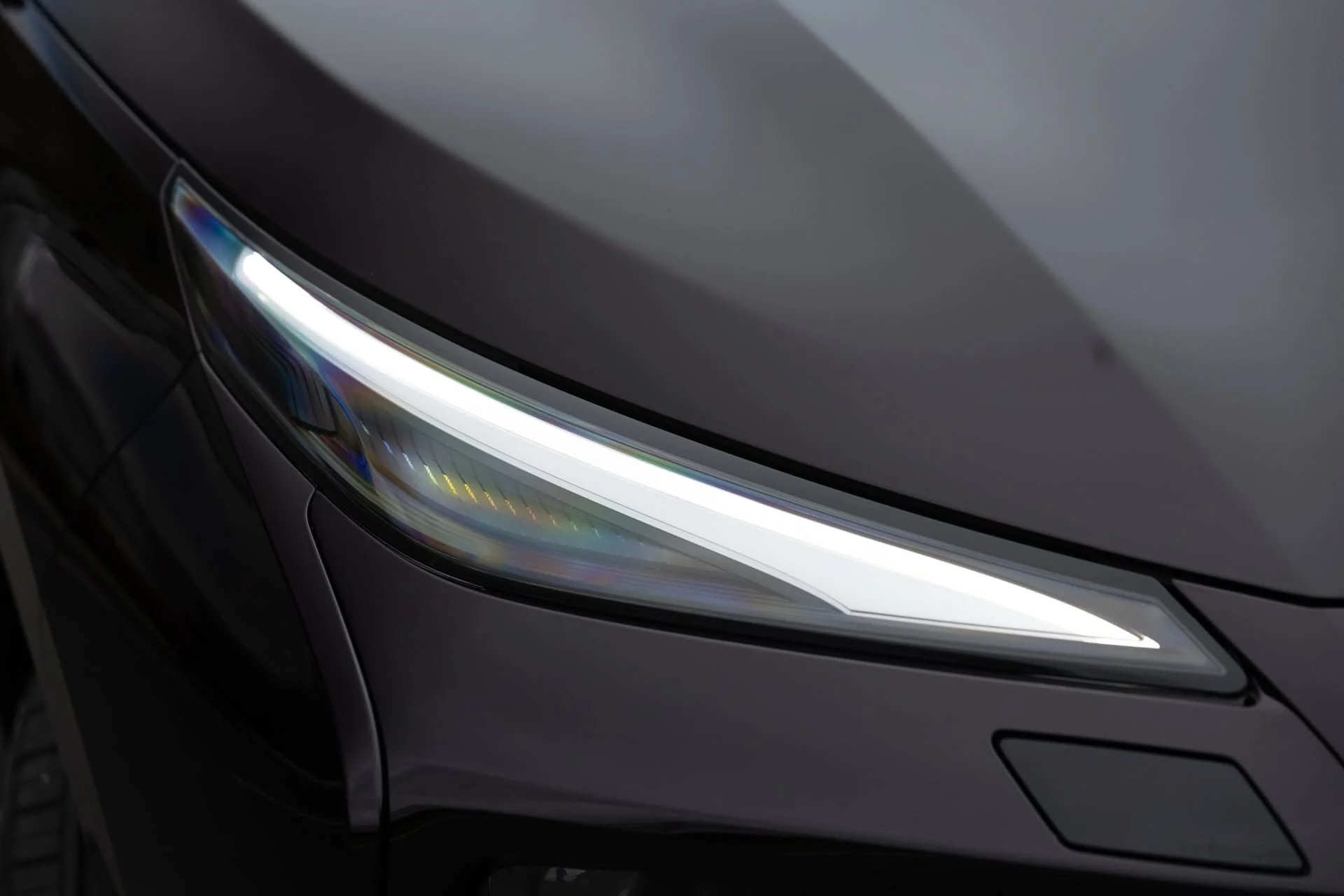Close-up of a modern car's front with headlight and part of the hood visible.