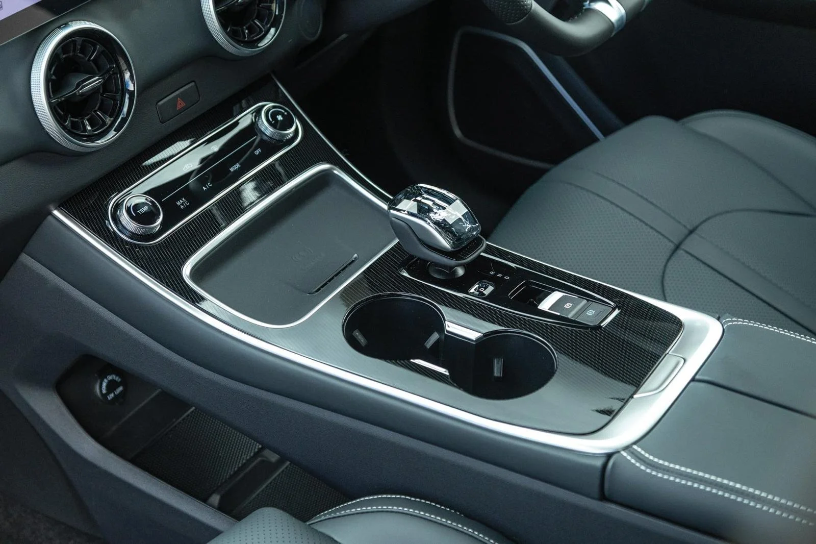 Interior of a modern car showing the center console with gear shifter, cup holders, and climate control panel.