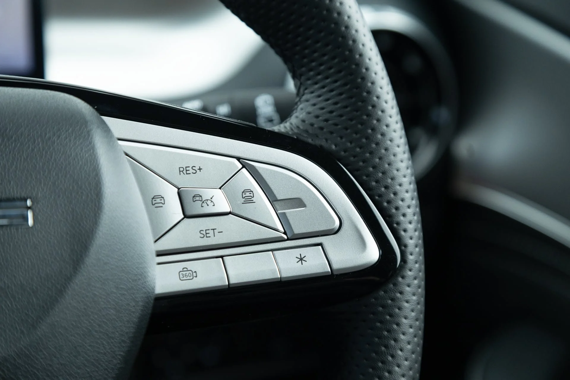 Close-up of a car steering wheel with control buttons for cruise control and other features.