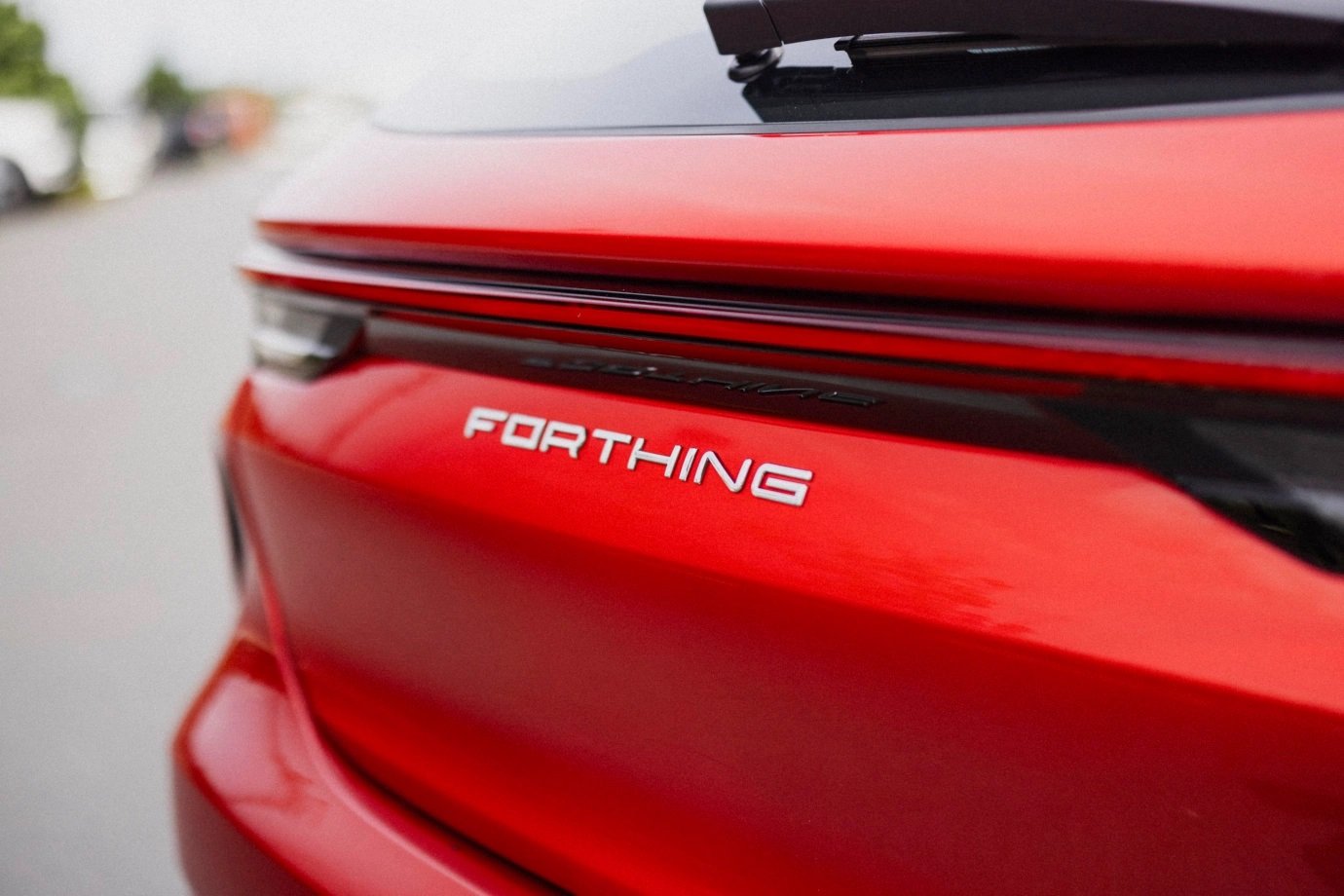 Close-up of the rear of a red car with the model name 'Forthing' in white letters.
