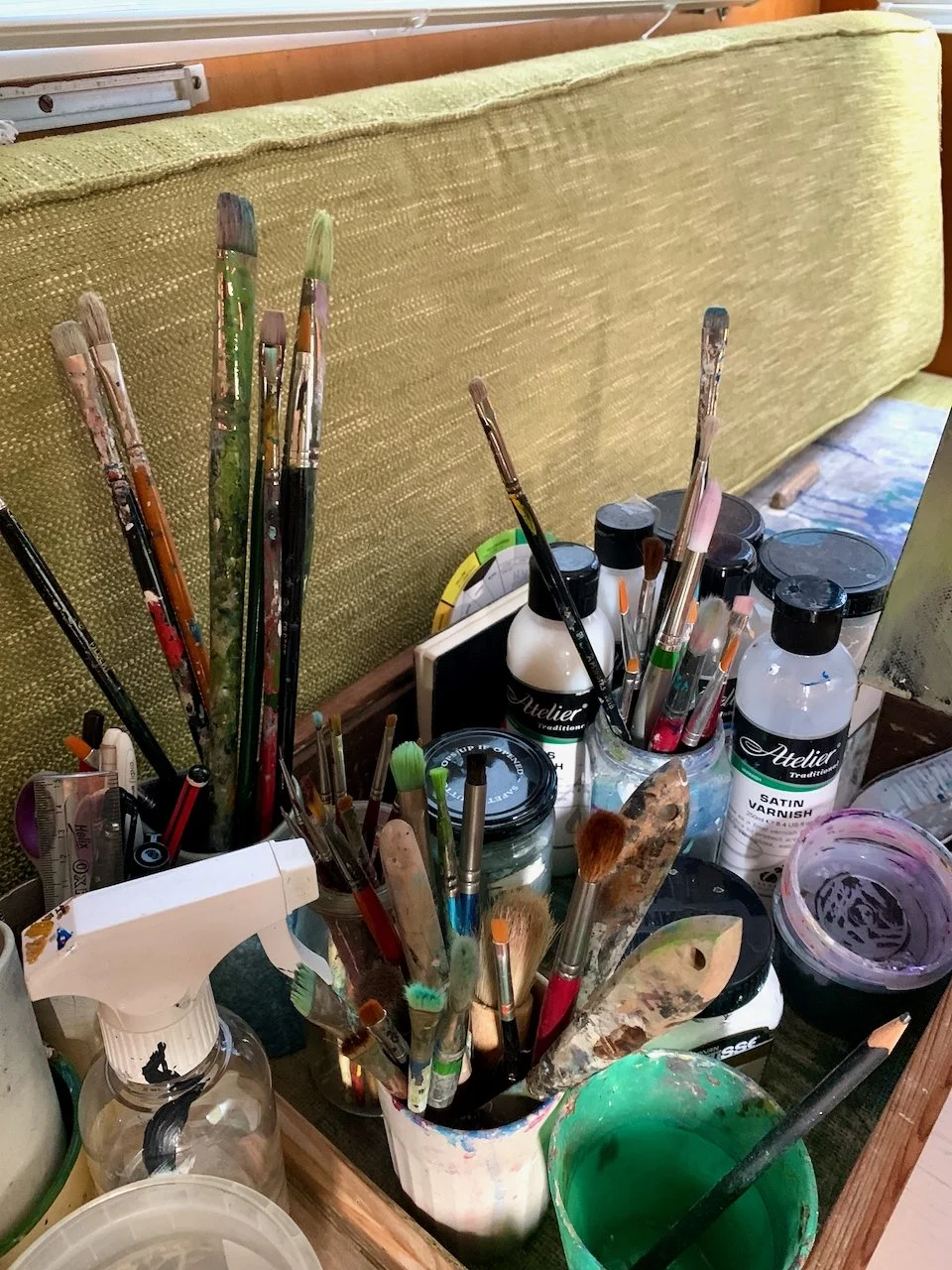 A collection of paintbrushes, paints, and art supplies on a table.