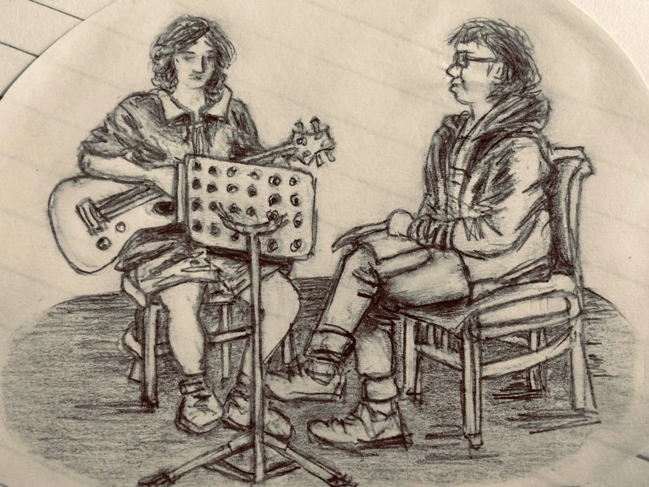 A pencil sketch of two people sitting indoors. The person on the left is playing an acoustic guitar, sitting on a stool, with a music stand in front. The person on the right is seated on a wooden chair, wearing glasses and a hoodie, listening attenti