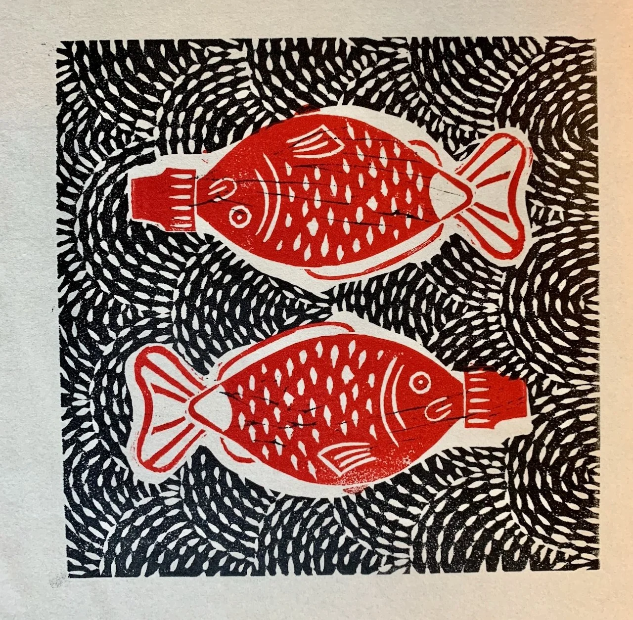 Two red fish illustrations facing each other on a white background, surrounded by a black pattern resembling waves or scales.