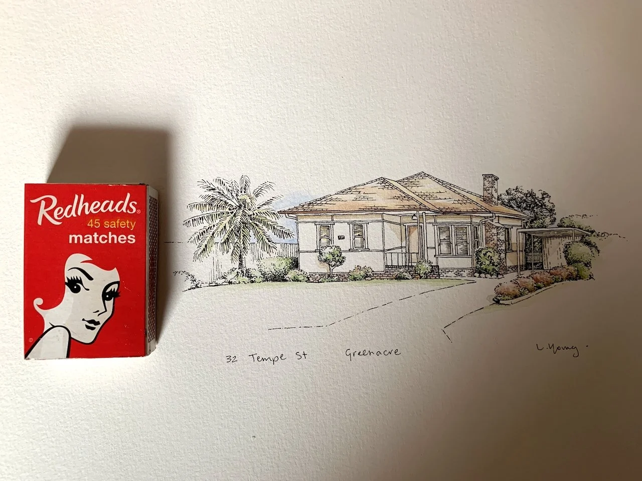 Hand-drawn illustration of a house with landscaping, palm trees, and a curved driveway, with a box of Redheads safety matches on the left side of the image.