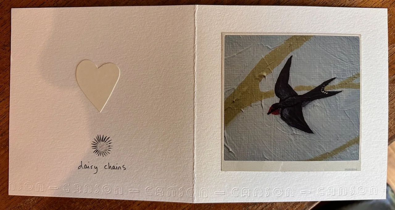 A scrapbook page with a small beige heart and a black and red swallow illustration, labeled "daisy chains."